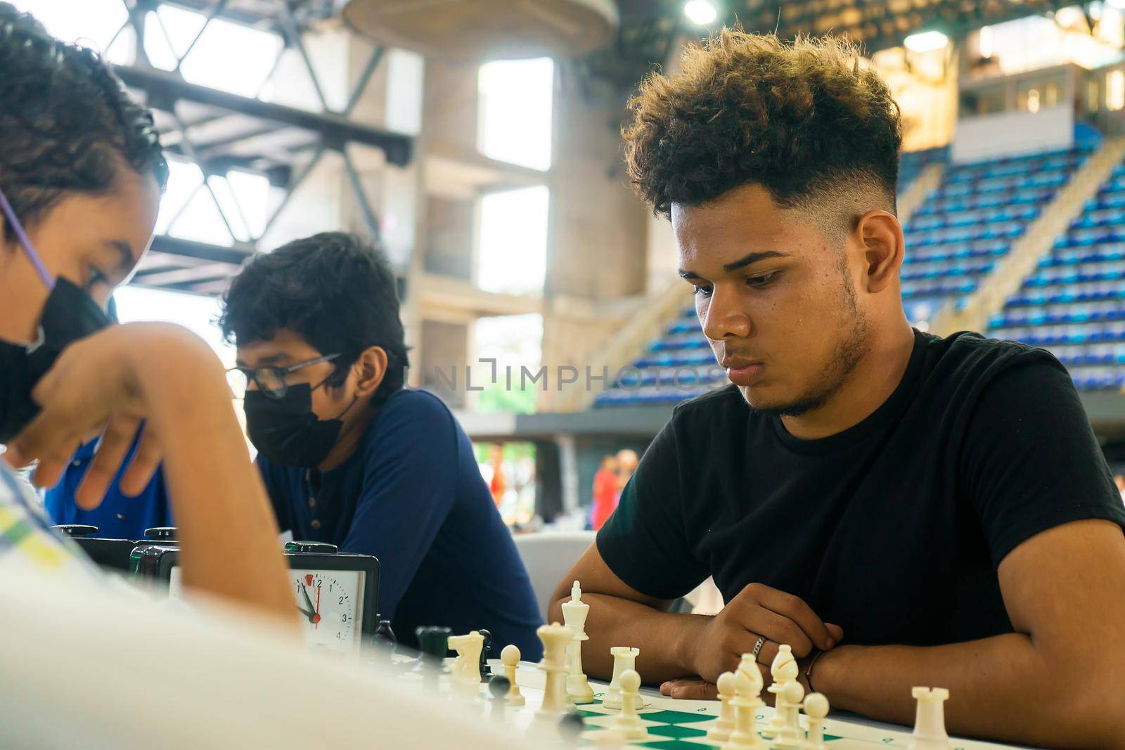 Young Latin man thinking about his move during a chess game in a gym by cfalvarez
