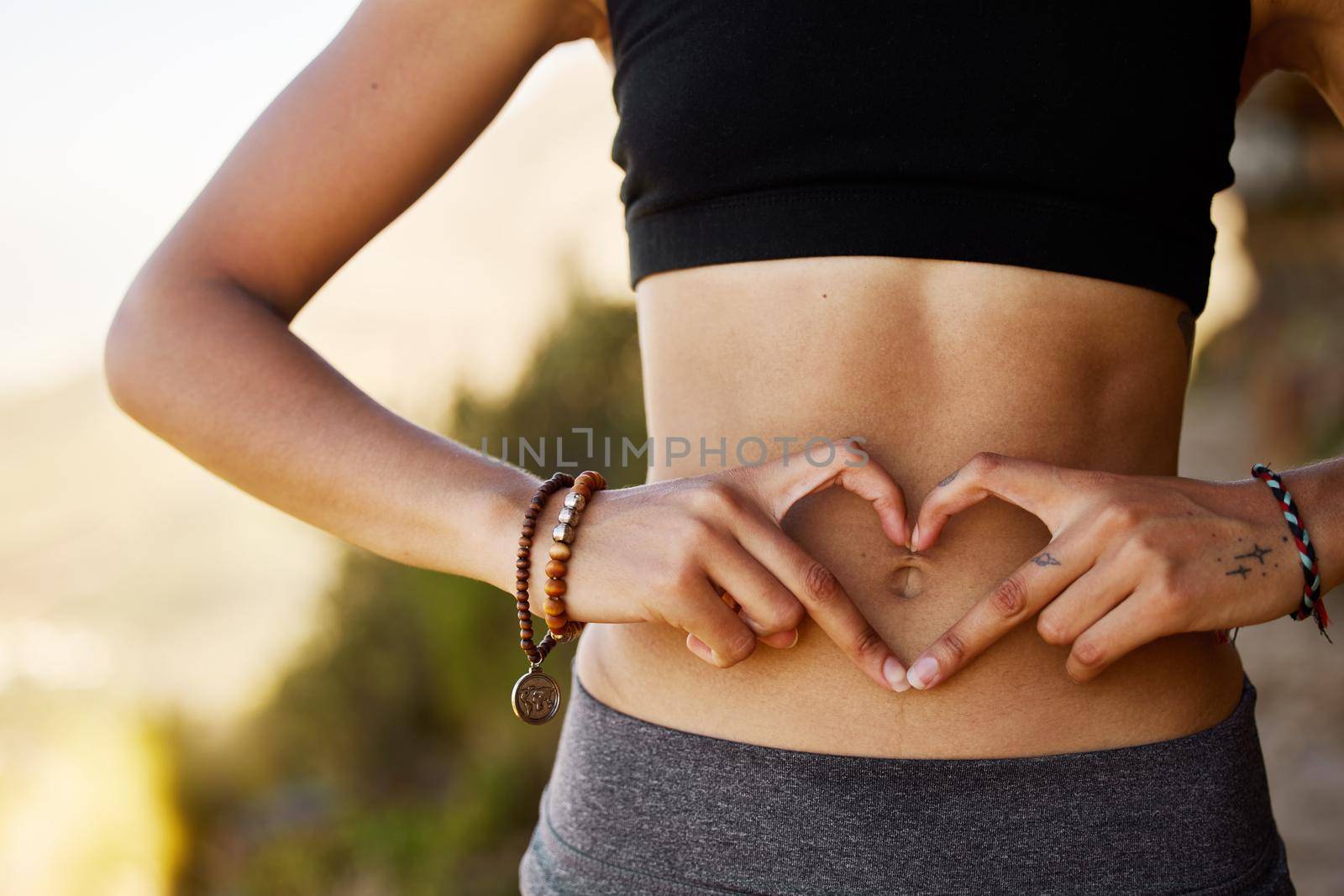 Cropped shot of a young woman forming a heart shape over her stomach.