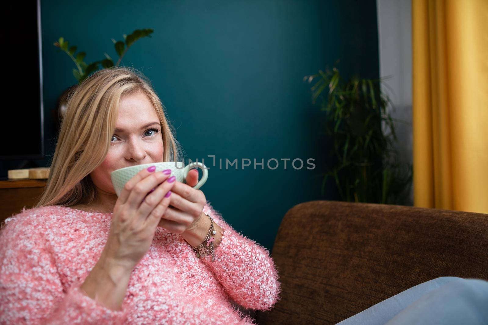 A relaxed girl enjoys an aromatic cup full of hot coffee.