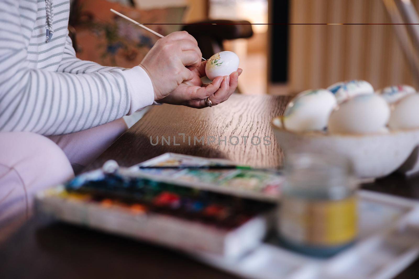 Process of woman paiting a water colors on fantasy chicken eggs. Female preparing for Easter egg festival.