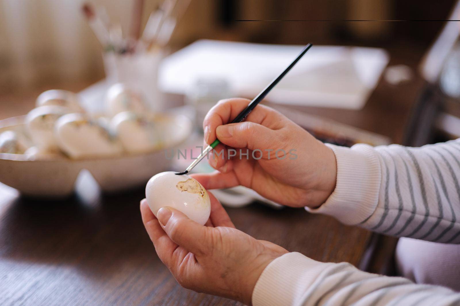 Woman painting a water colors on fantasy chicken eggs for Easter egg festival. Female drawing little yellow chick. The symbolic of Easter egg festival concept.