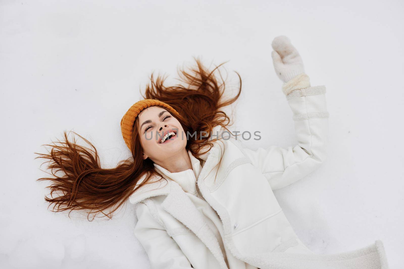 cheerful woman winter clothes with a hat lies on the snow Lifestyle by SHOTPRIME