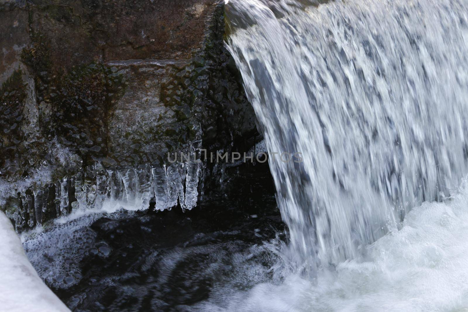 Flowing water close-up and icicles with ice.