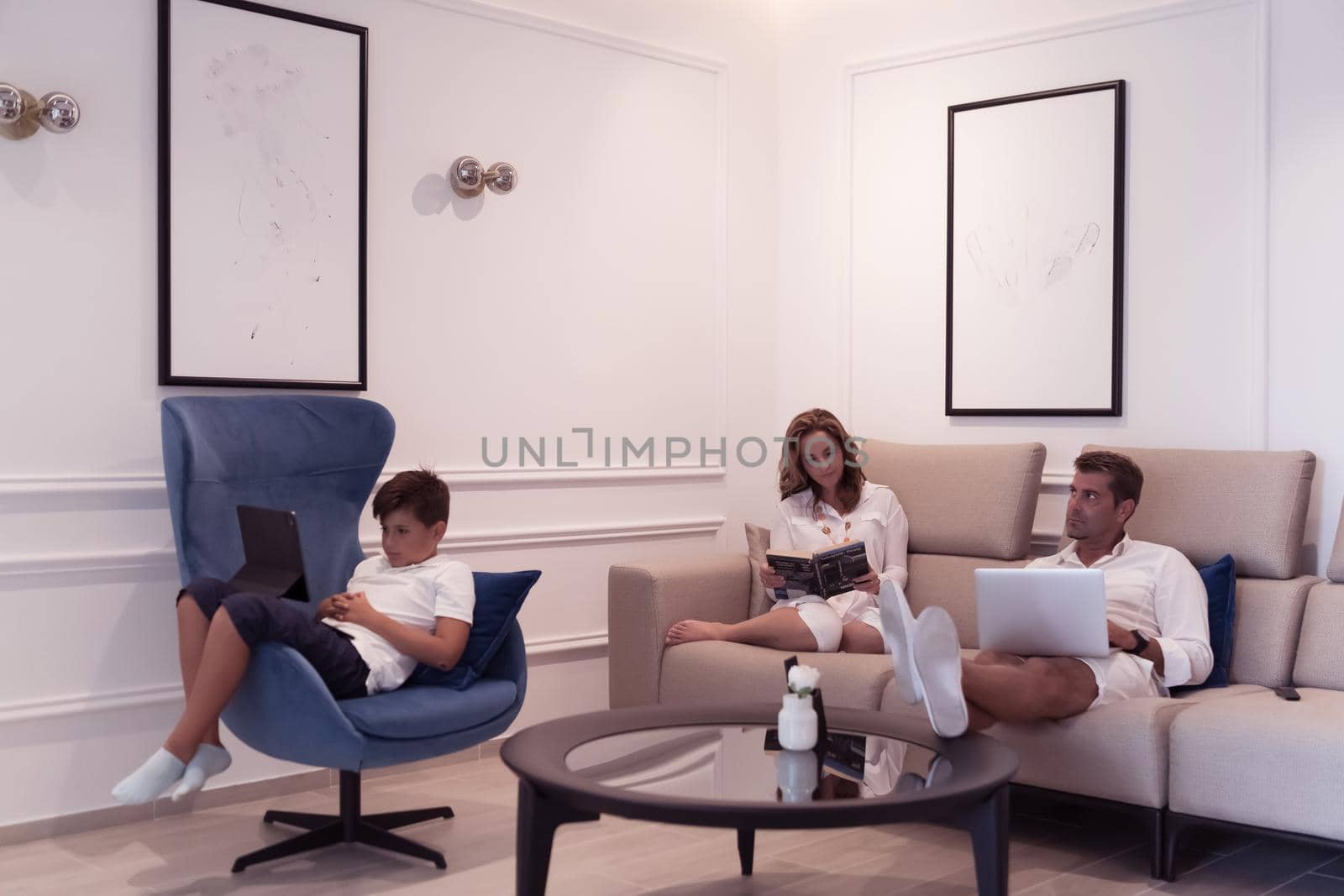 A modern family enjoys a vacation in their luxury home. The family spends time on modern devices, tablets and laptops. Selective focus by dotshock