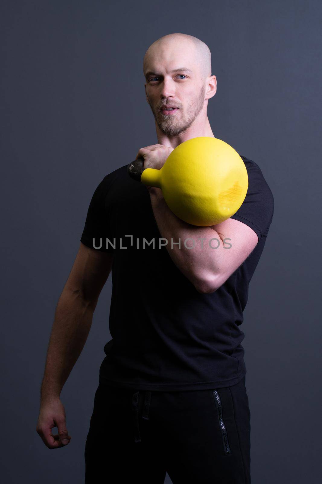 Guy with a yellow kettlebell gym anonymous young male, for sporty lifestyle for painted from floor sportswear, southeast filipino. Healthy bent health, cross hiit