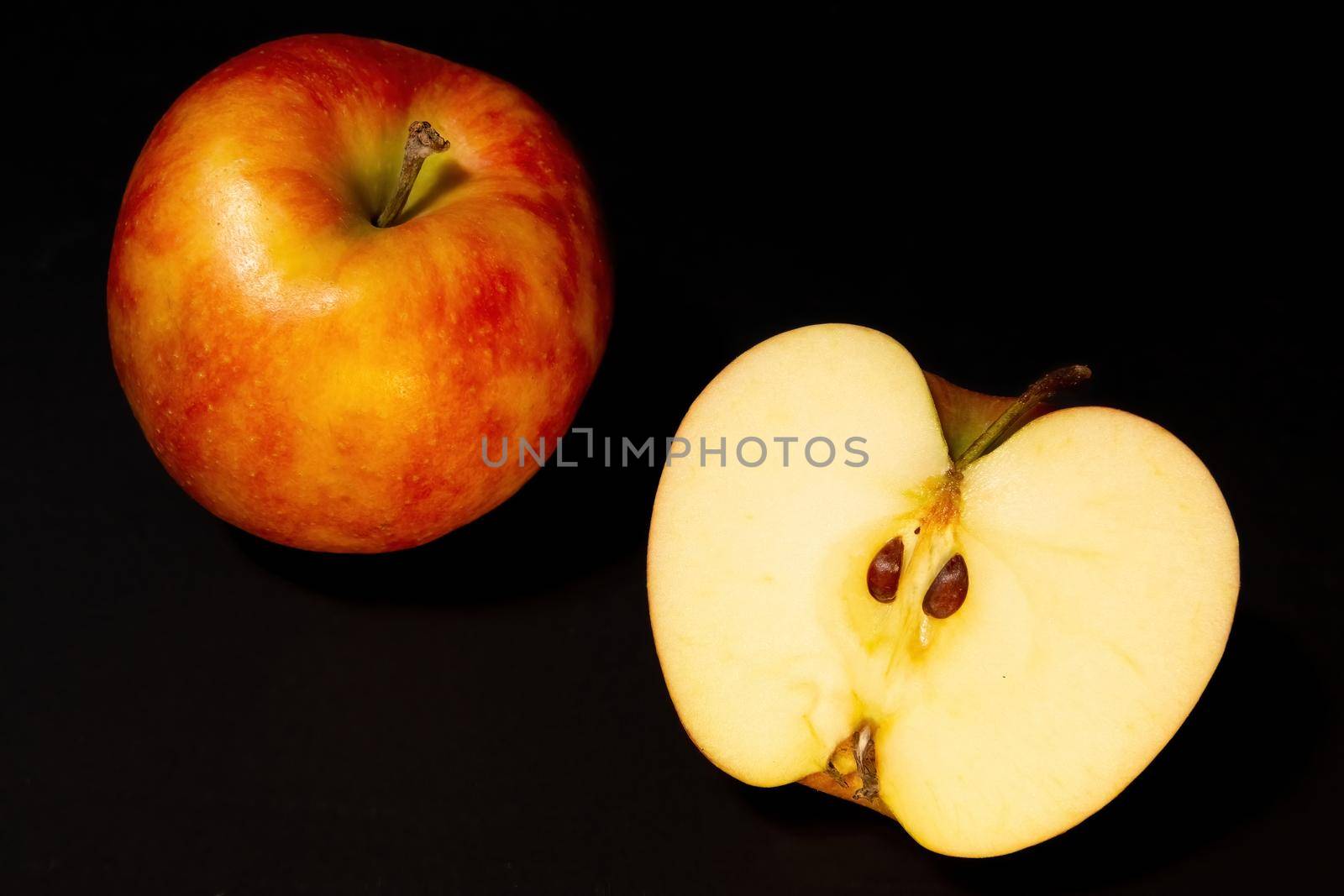 Ripe red apples on a dark background, whole apple and cut in half