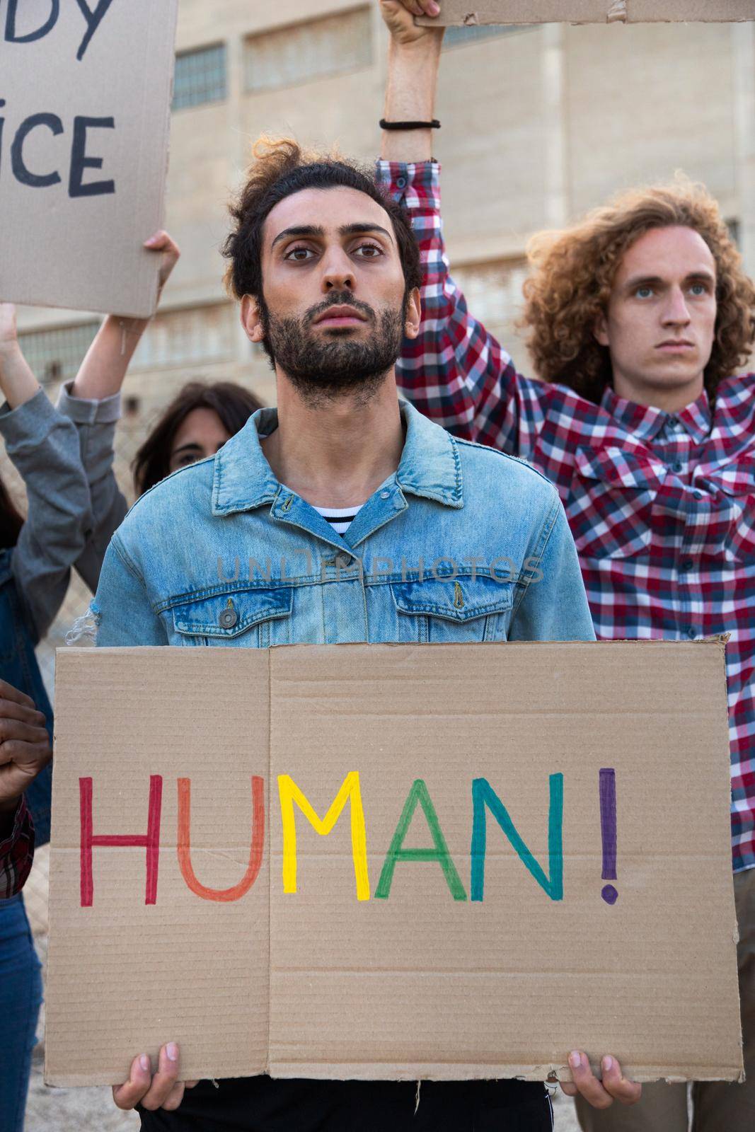 Young arab man protesting on a demonstration for LGBT rights holding cardboard banner. Vertical image. Activist concept.