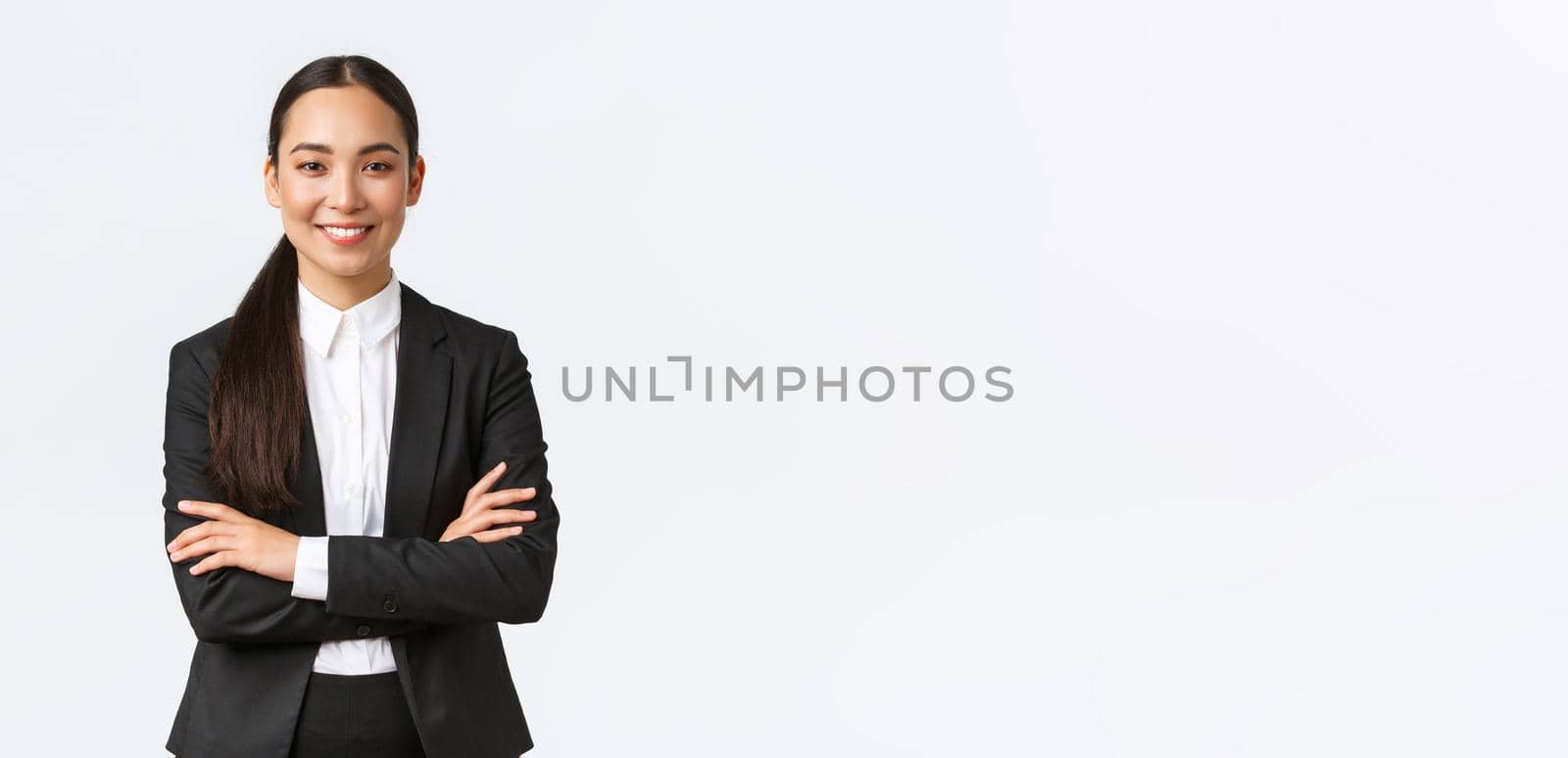 Successful young asian businesswoman in suit ready do business, cross arms confident and smiling. Female entrepreneur determined to win. Happy saleswoman talking to clients, white background by Benzoix