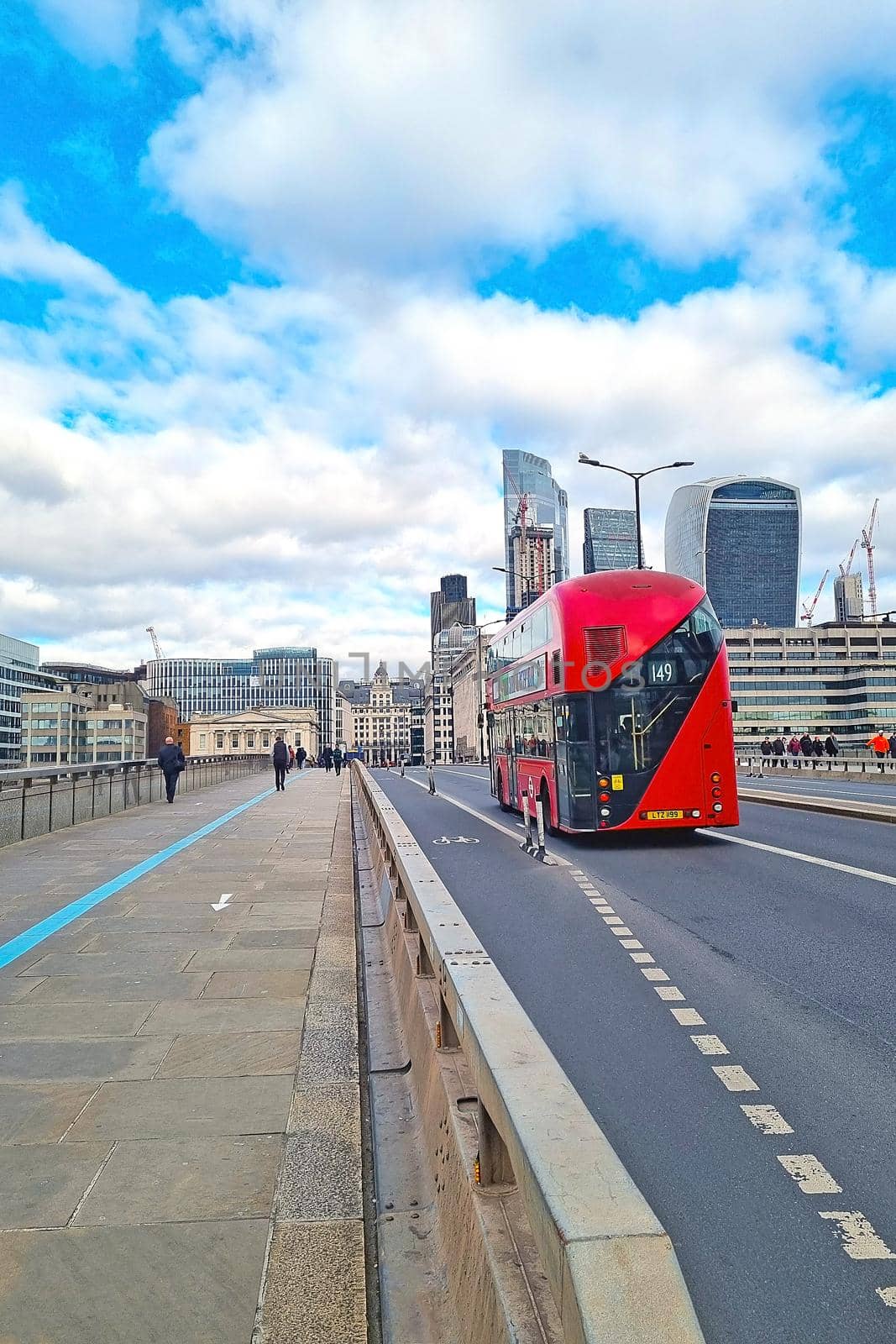 London, United Kingdom, February 4, 2022: A red double-decker bus drives over the bridge against the backdrop of tall buildings in London
