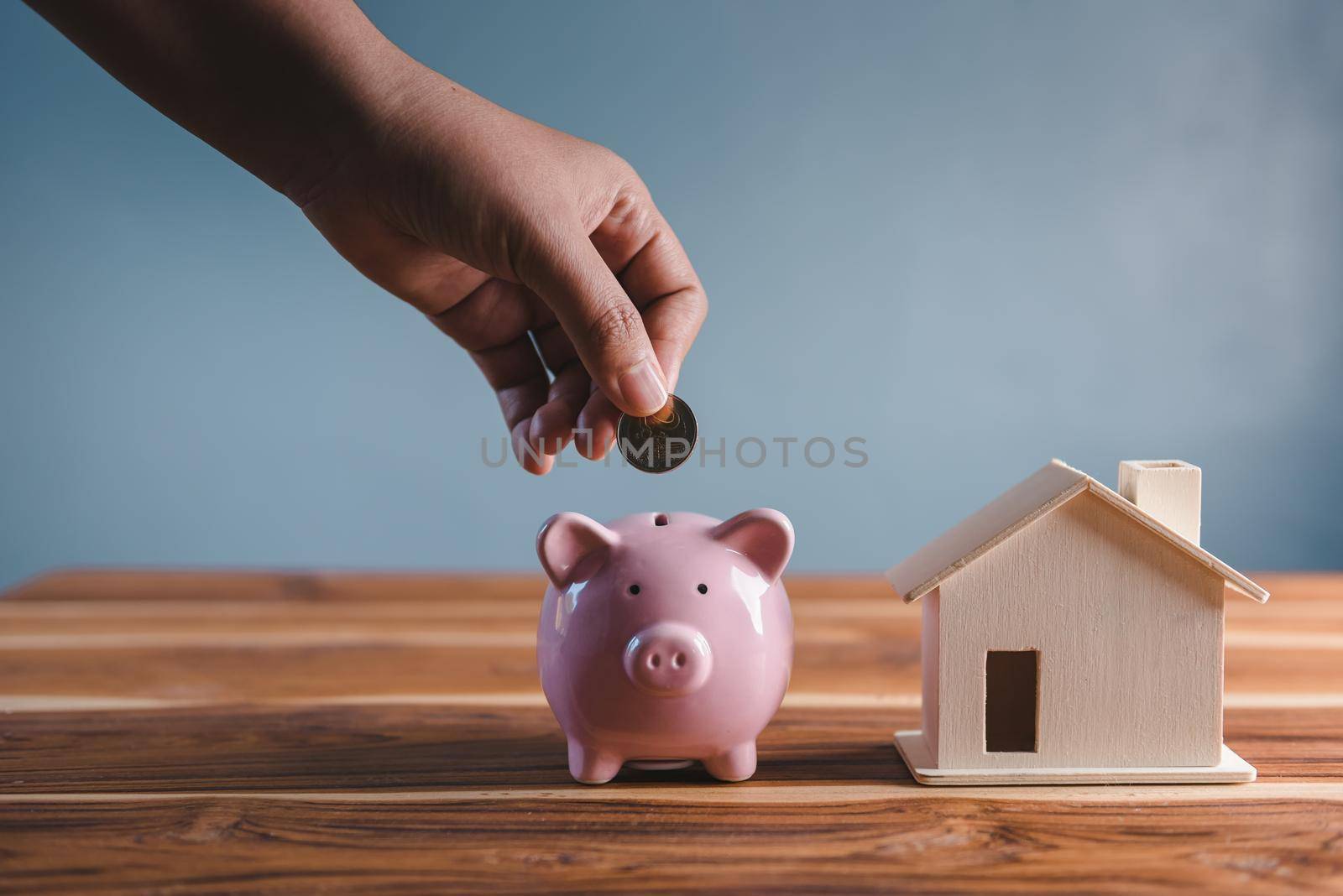 Money Savings for Future Property House Concept, Hand is Putting Coin Into Piggy Bank for Saving Future Housing Real Estate Ownership. Banking Fund for Investing House Asset and Real Estate