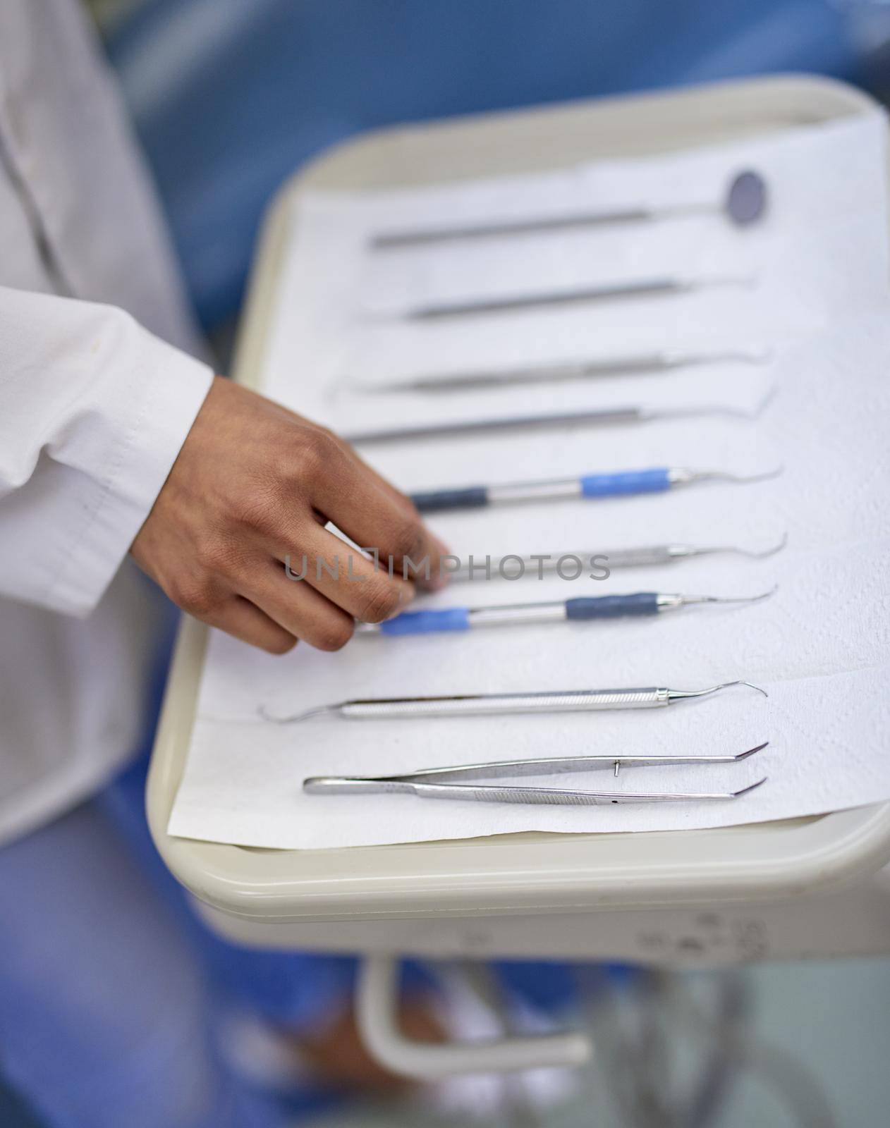 Lining up dental tools on a tray. Closeup shot of an unrecognisable dentist working with a tray of surgical instruments. by YuriArcurs
