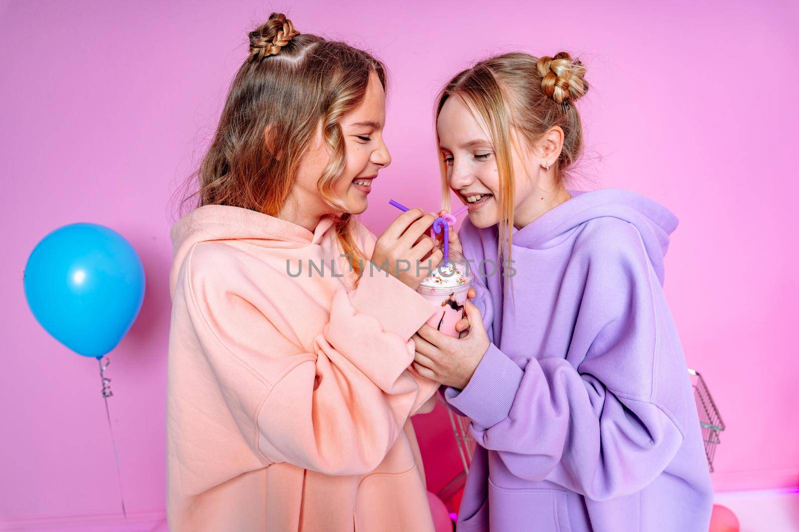 Two beautiful attractive funny joyful cheerful relaxed carefree girls dressed in casual fashion clothes isolated on hot pink background by Matiunina