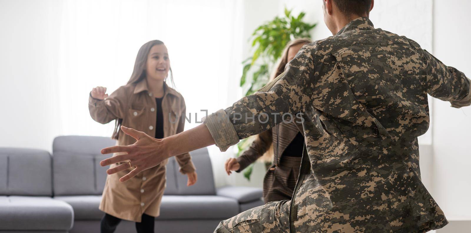 Happy veteran soldier comes back from the military and reunites with family. two children missed, home background by Andelov13