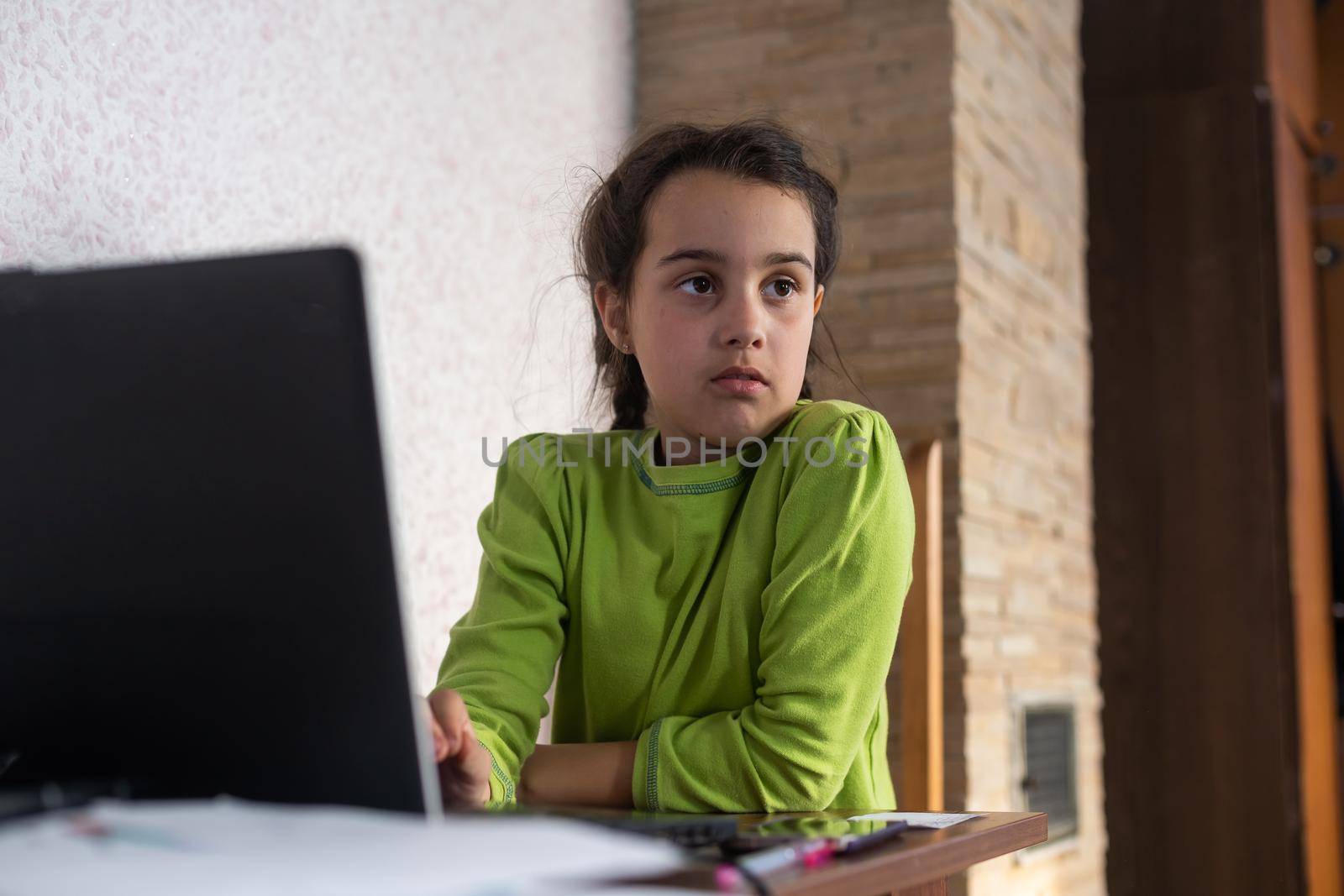 Child online. A little girl uses a laptop video chat to communicate learning while sitting at a table at home