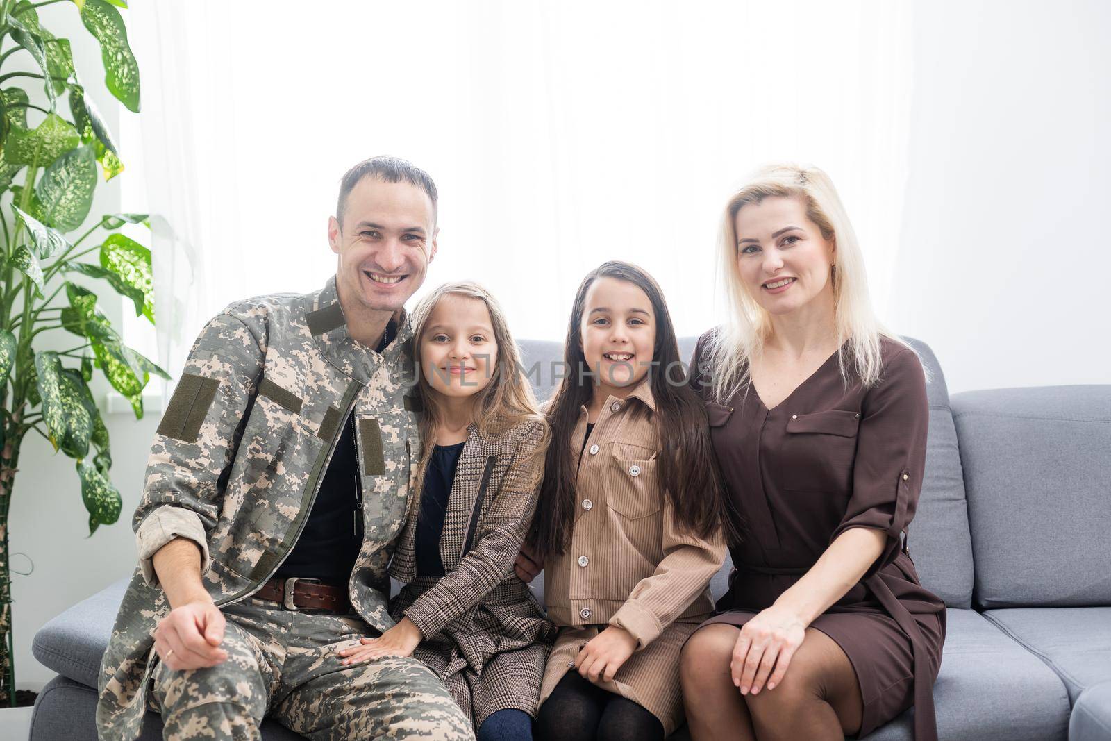 Soldier in camouflage and his family sitting at home by Andelov13