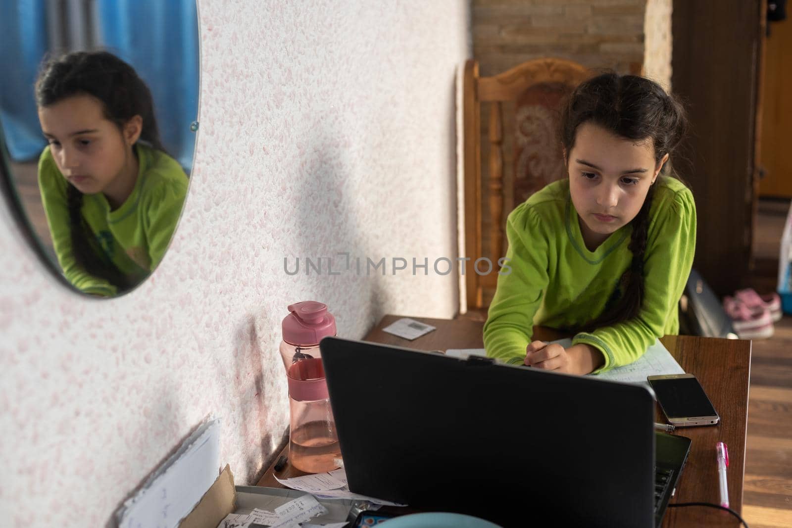 children, education and distant learning concept - little student girl in earphones with laptop computer at home