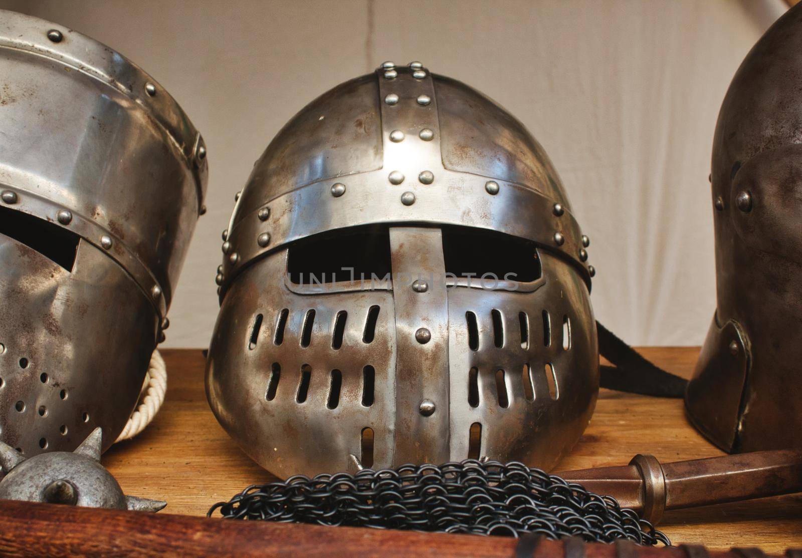 Shiny metal helmets of medieval knights with traditional weapons at a middle age theme festival