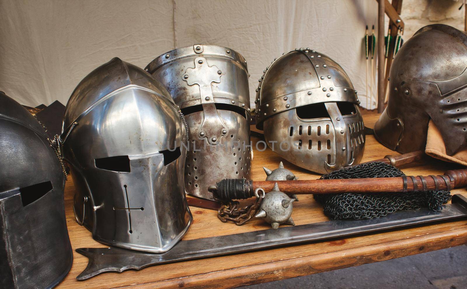 Shiny metal helmets of medieval knights with traditional weapons at a middle age theme festival