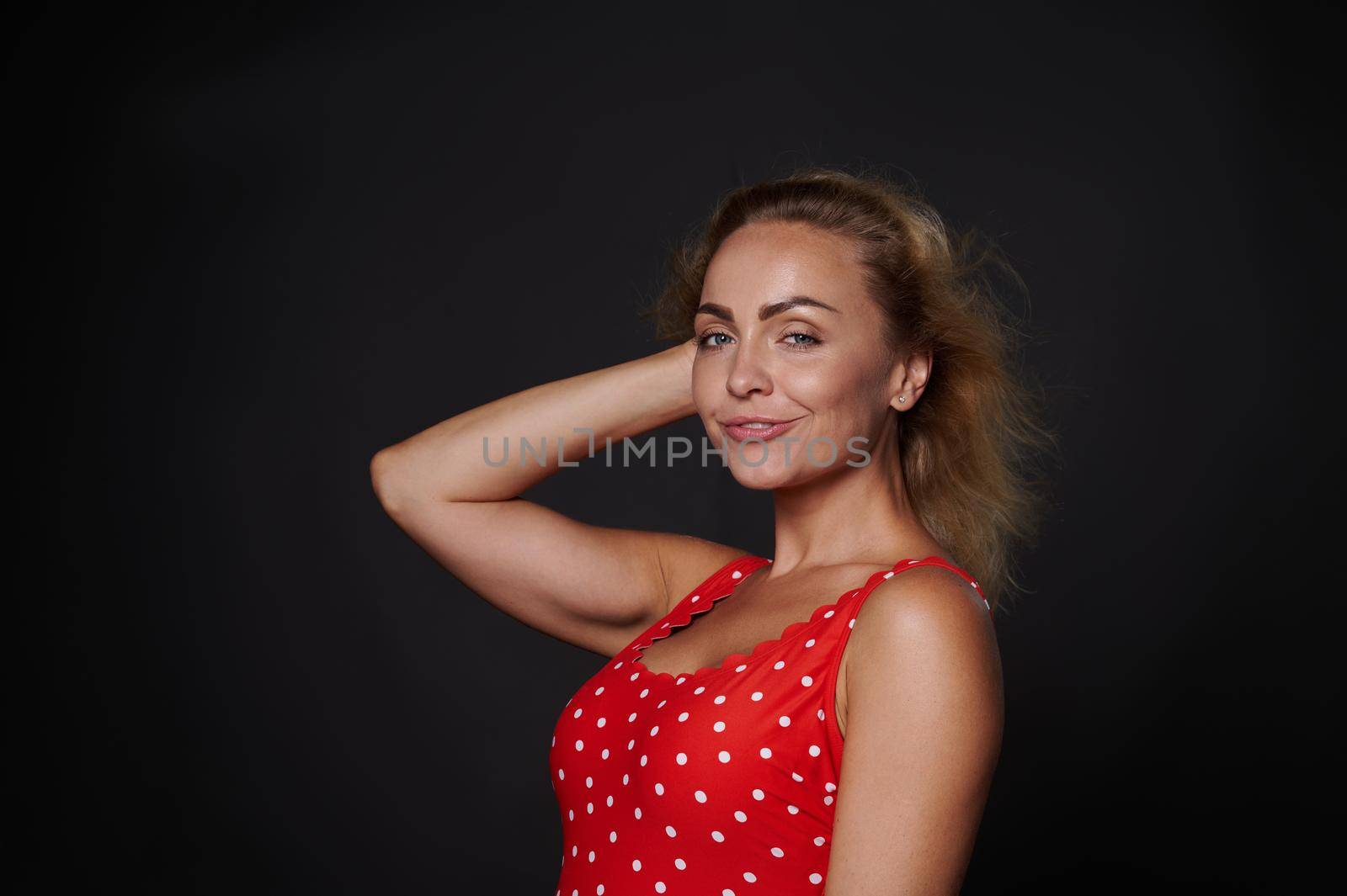 Attractive beautiful 30 years old Caucasian woman in red swimsuit isolated over black background with copy ad space. by artgf