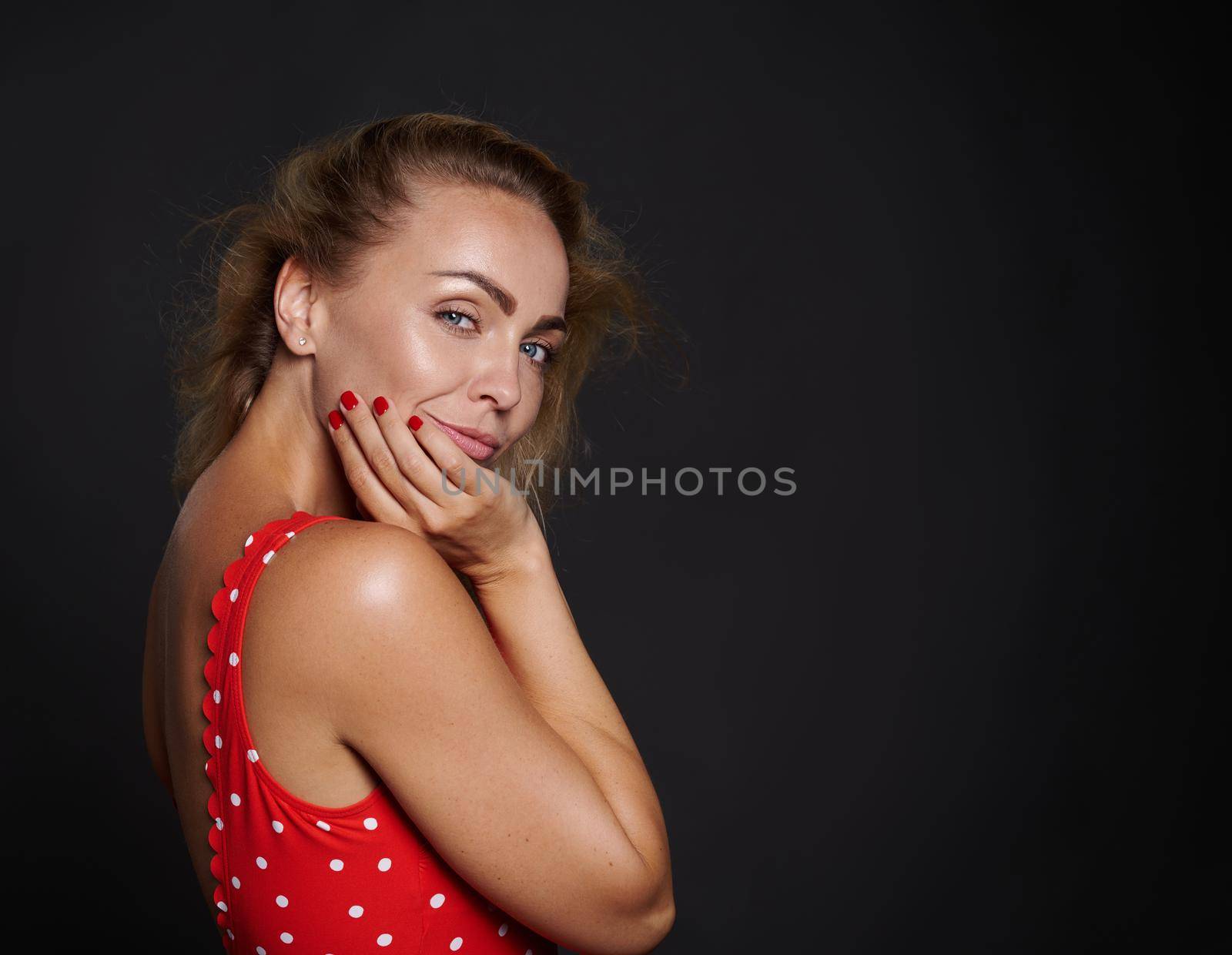 Fashion photo of blonde beauty with natural make-up, healthy body and tanned skin isolated over black background