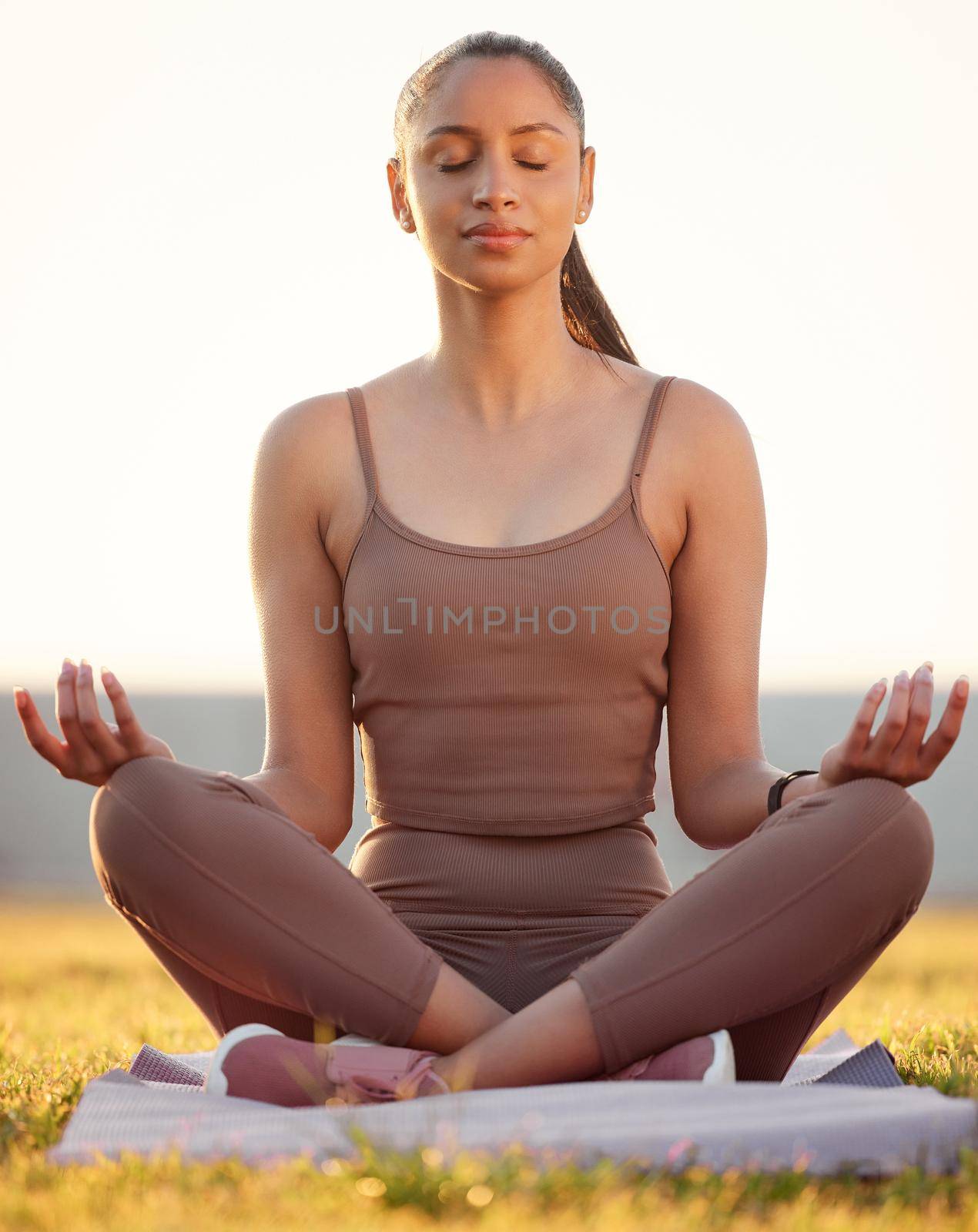 Shot of a sporty young woman meditating while exercising outdoors.
