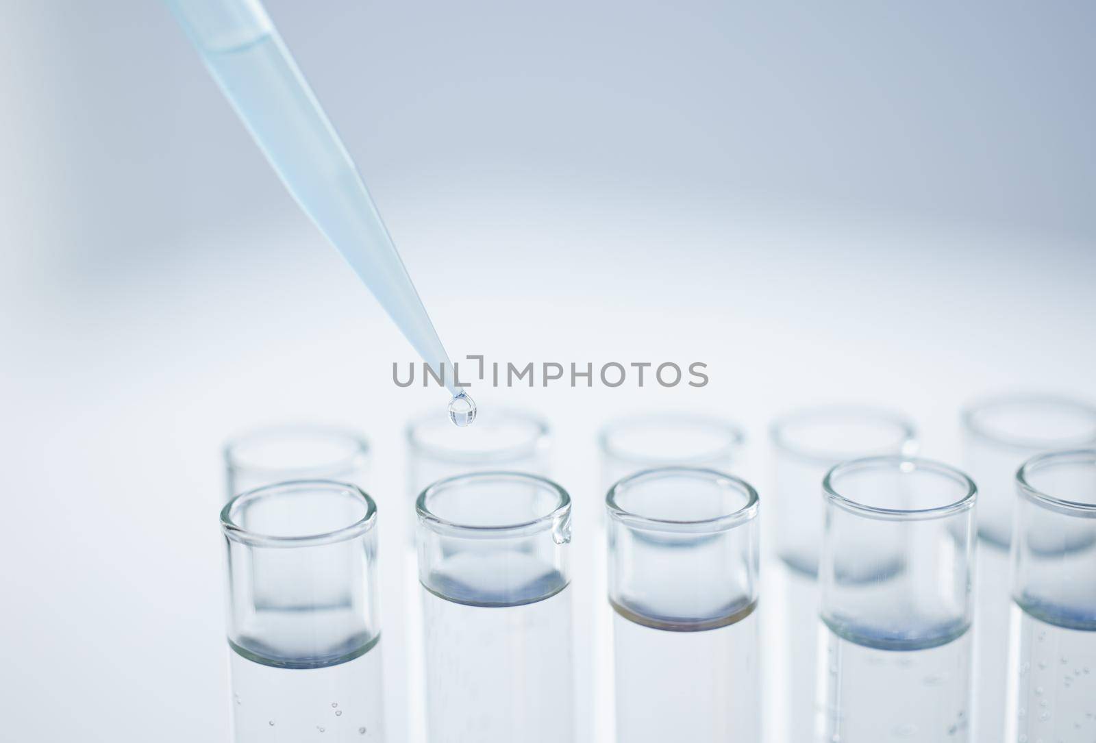 Practising precision in the lab. Closeup shot of a dropper being used to fill test tubes in a lab. by YuriArcurs