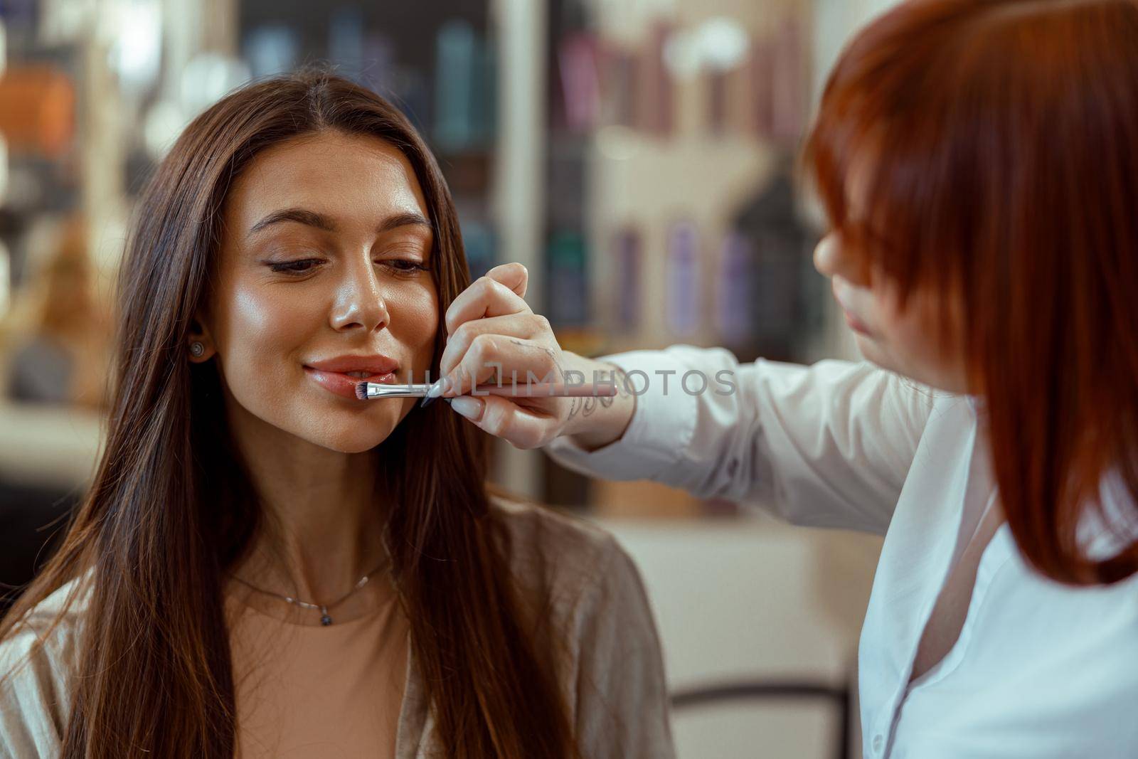 Professional makeup artist applying lipstick with a brush in beauty salon by Yaroslav_astakhov