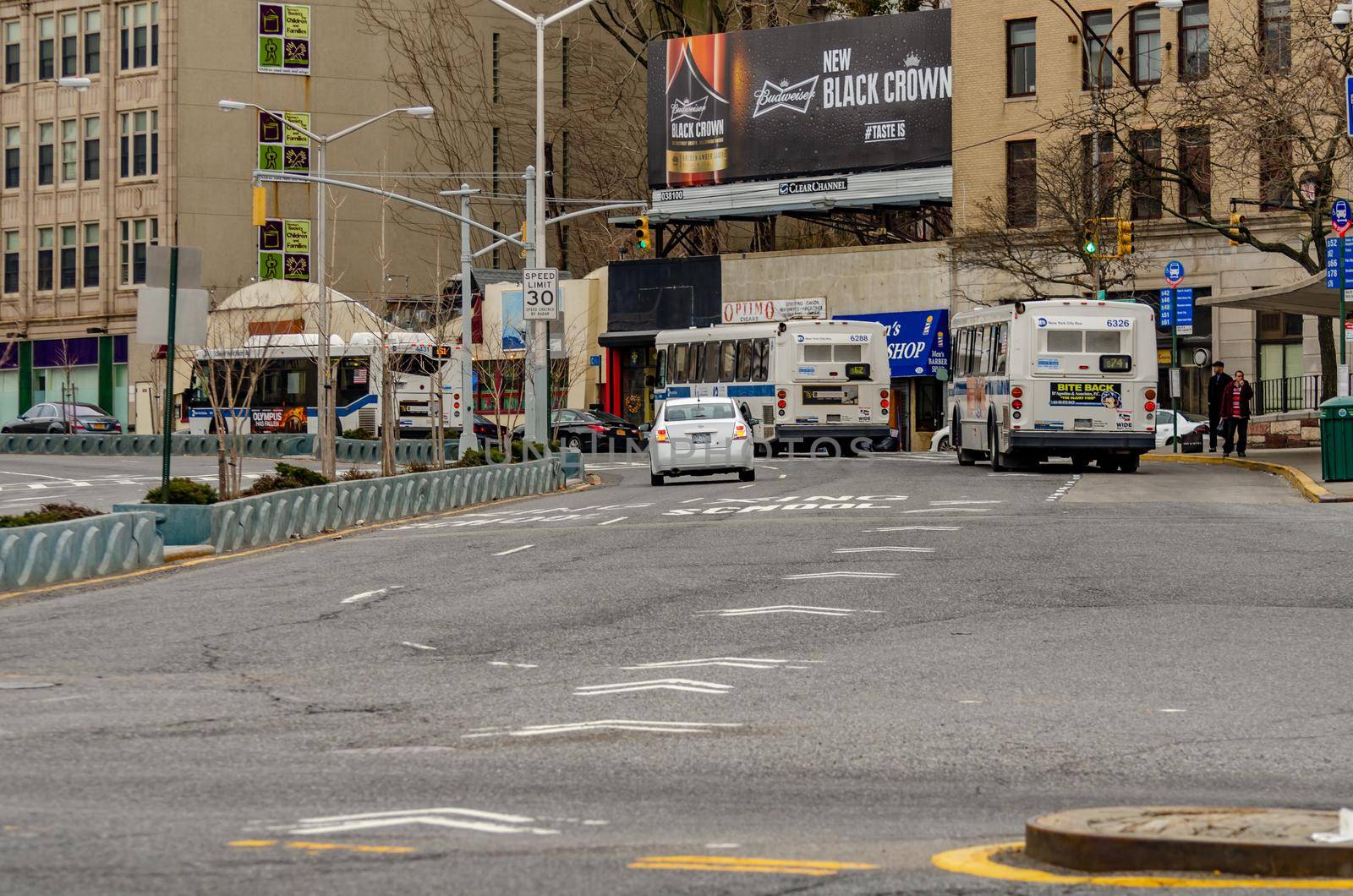 Staten Island, New York City, Buses and cars leaving the Ferry Terminal Station, rear view, during winter day retail stores and advertisement in the background, horizontal