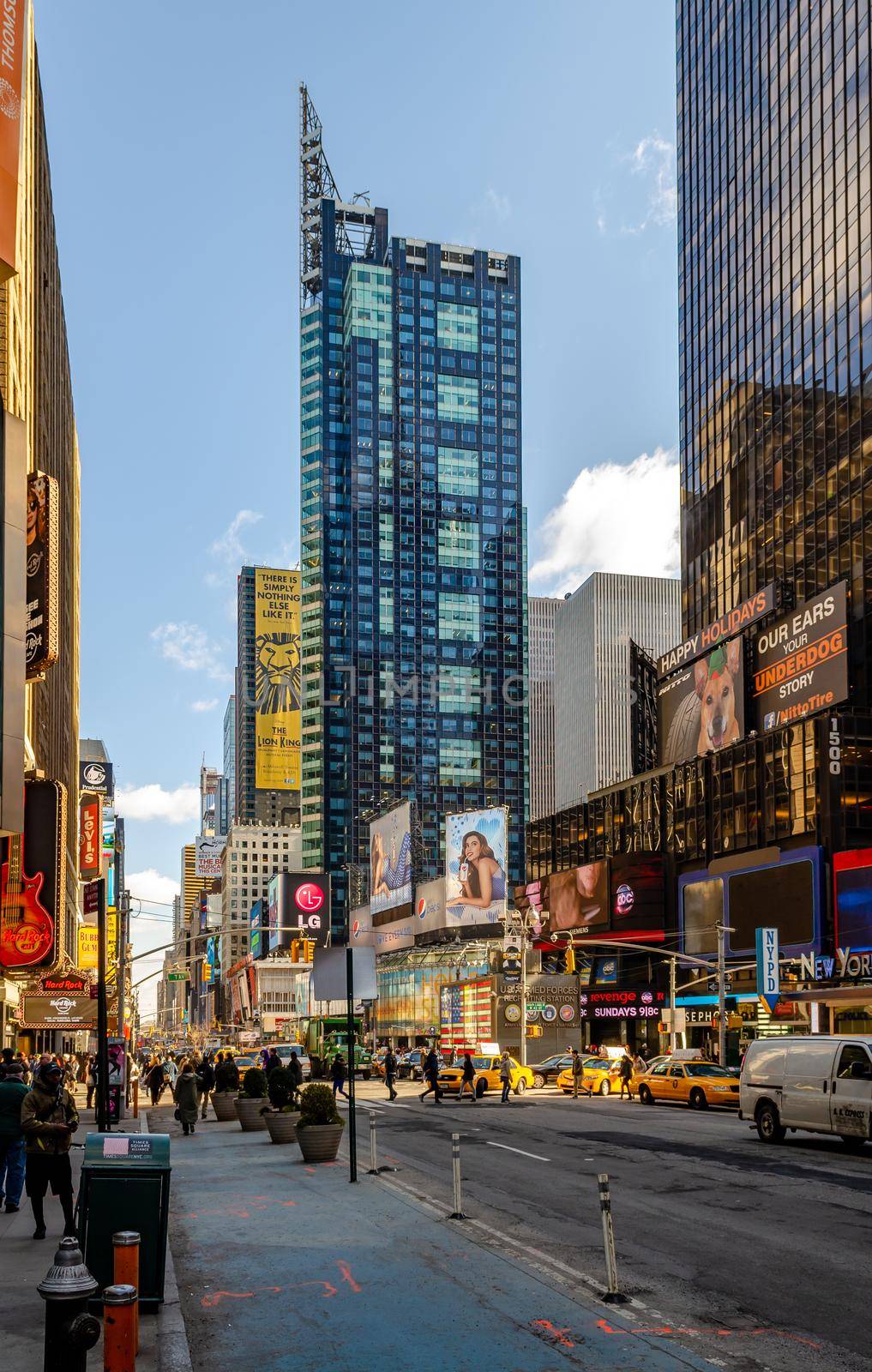 Time Square New York City with skyscraper, lots of advertisement, people walking around, traffic and yellow Taxi Cabs, low angle view during sunset, vertical