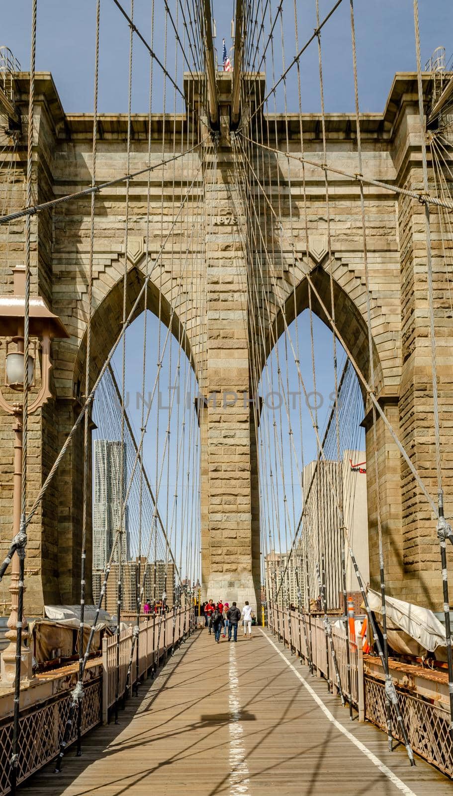 People walking on Brooklyn Bridge during daytime in winter, New York City, construction area on the left and right side on the bridge, vertical
