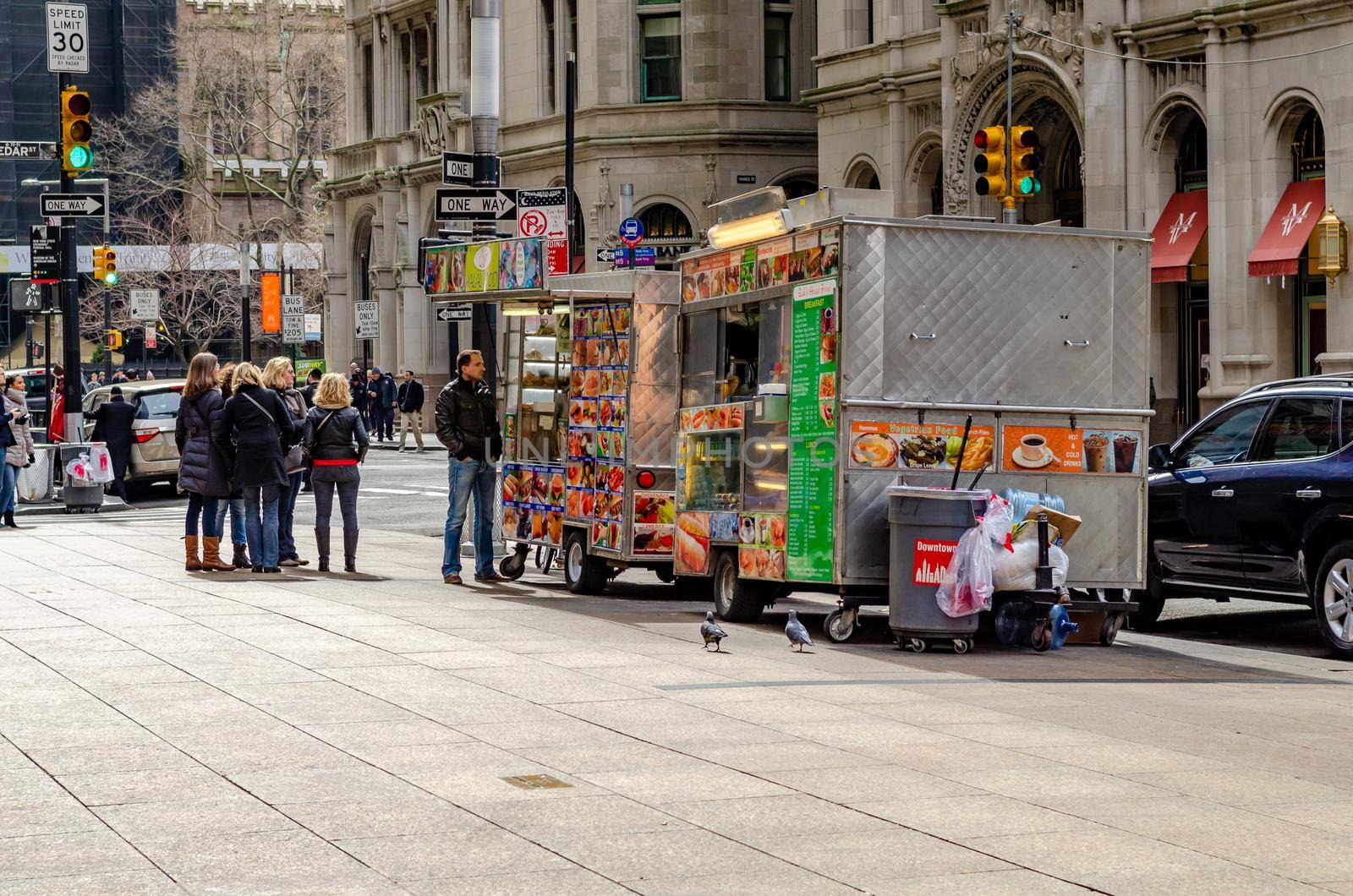 Two different Street Food Trucks in Manhattan on a sidewalk, People waiting in line to get food, New York City, during winter, horizontal
