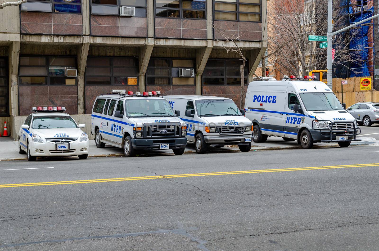 NYPD Different New York Police Department cars and trucks and van parked next to each other at a police station in Harlem next to the street, New York City, during winter day, horizontal