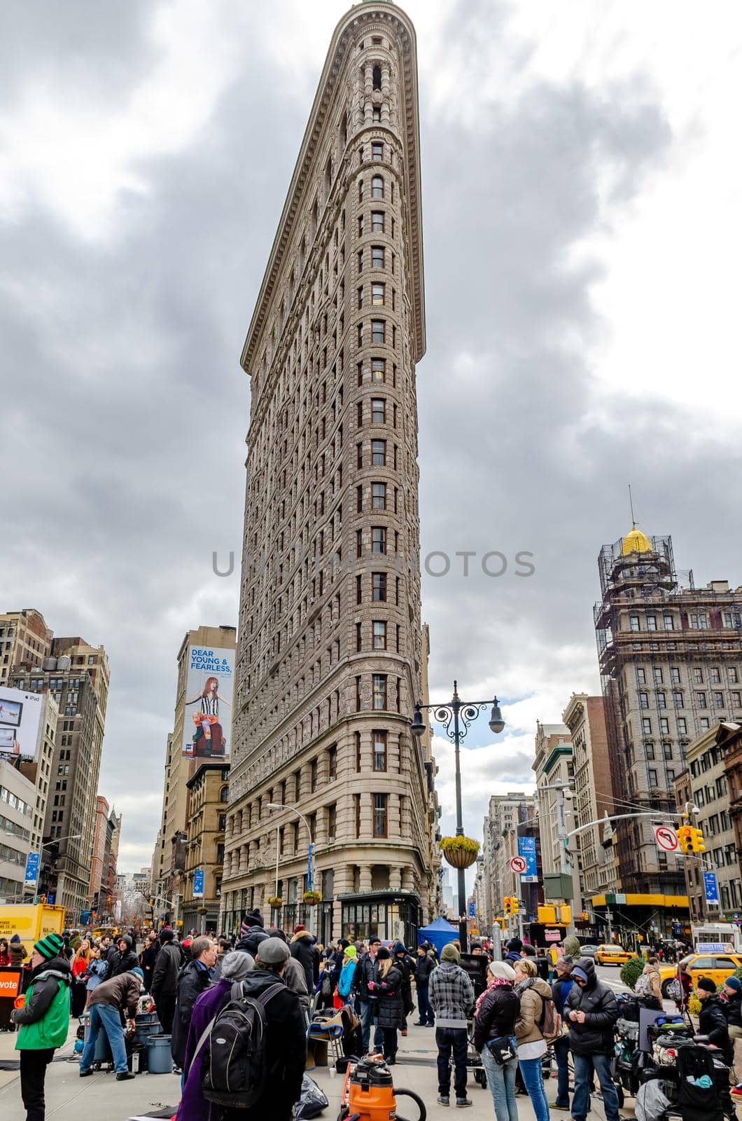 Flatiron Building New York City with lots of People standing in the forefront low angle view during daylight, overcast, vertical