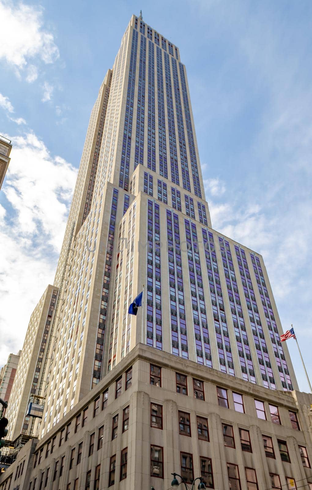 Empire State Building New York City, low angle side view during a sunny winter day, American flag at the bottom of the Building, vertical