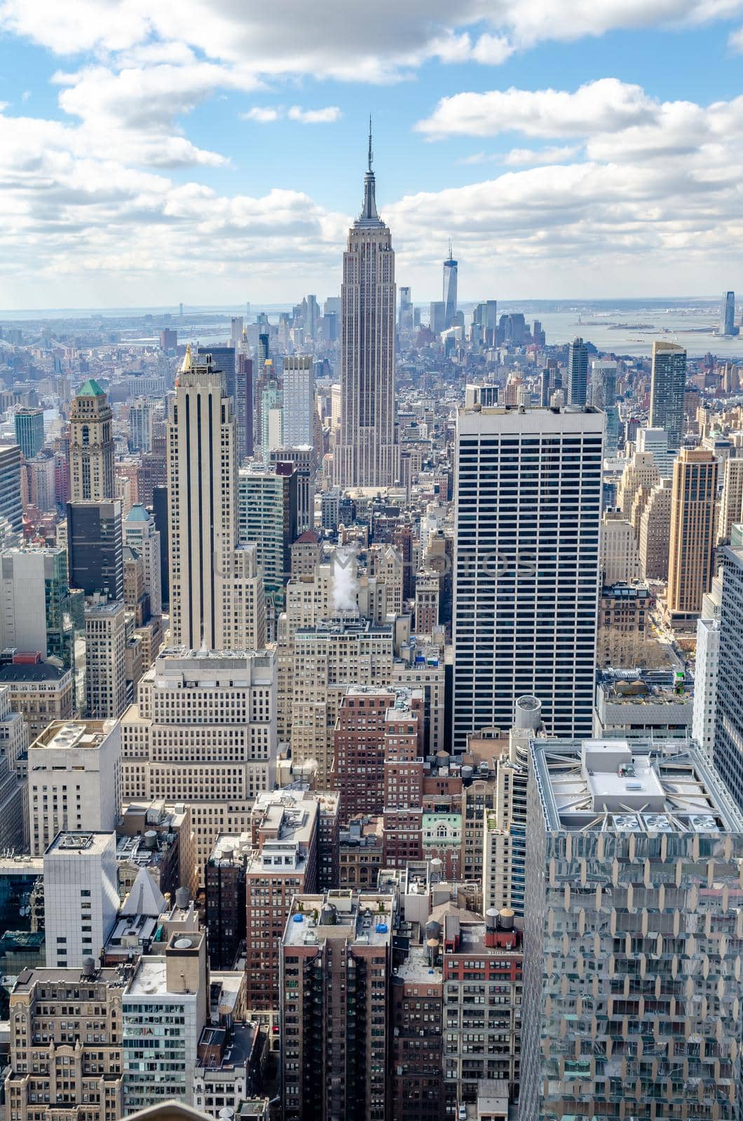 Manhattan Skyline with Empire State Building and one World Trade Center construction site, View from Rockefeller Center, New York City during winter, vertical