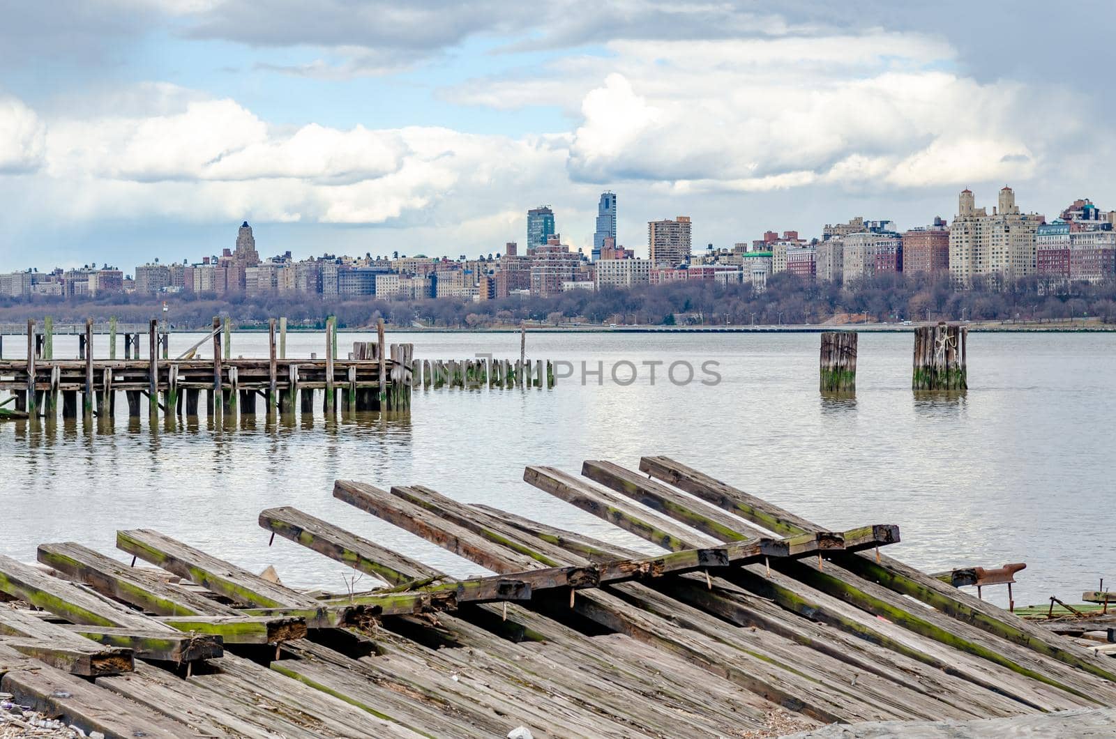 View of Manhattan Skyscraper, New York City with wooden landing stage and Hudson river in front during cloudy winter day, horizontal