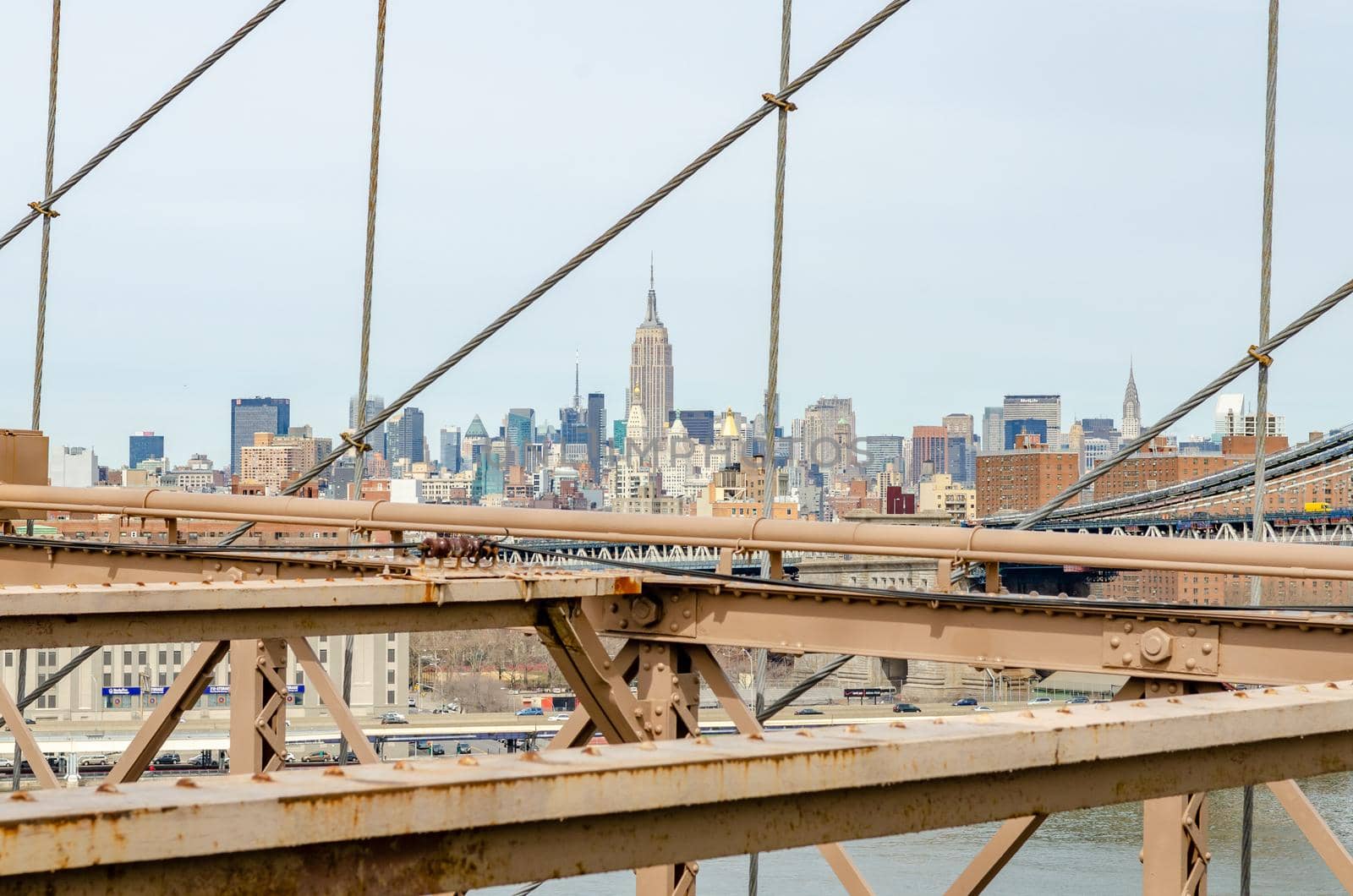 Manhattan Bridge with brown steel construction of Brooklyn Bridge in forefront, New York City, Empire State Building in the Background, horizontal