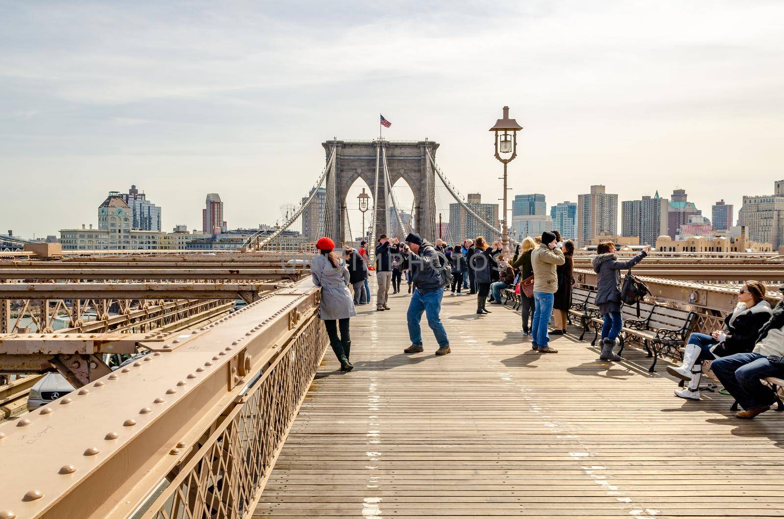 Brooklyn Bridge New York City with tourists taking photos and relaxing on the bridge by bildgigant