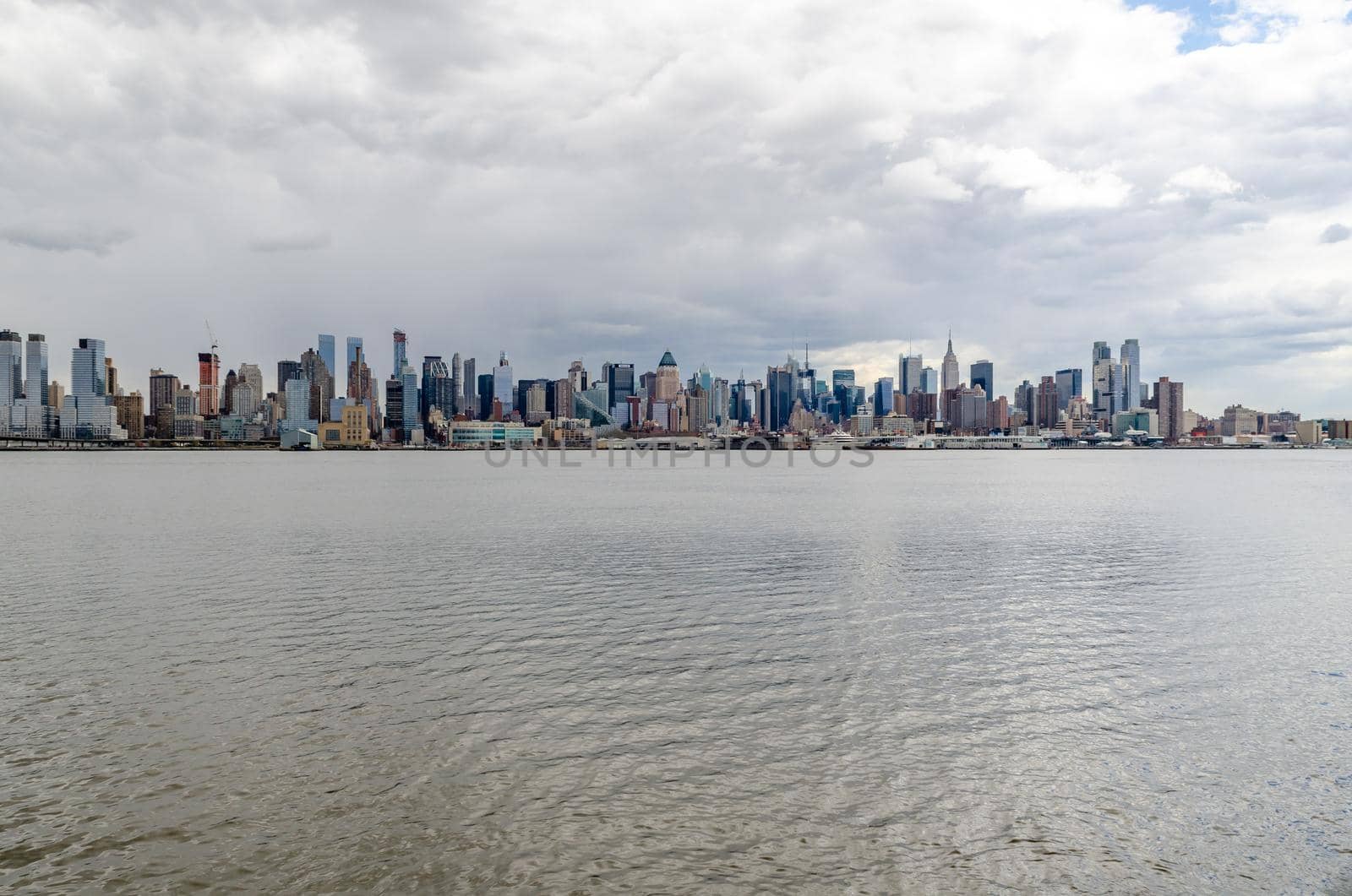 Wide angle shot of New York City Manhattan Skyline with Empire State Building and Hudson river in front during cloudy winter day, horizontal