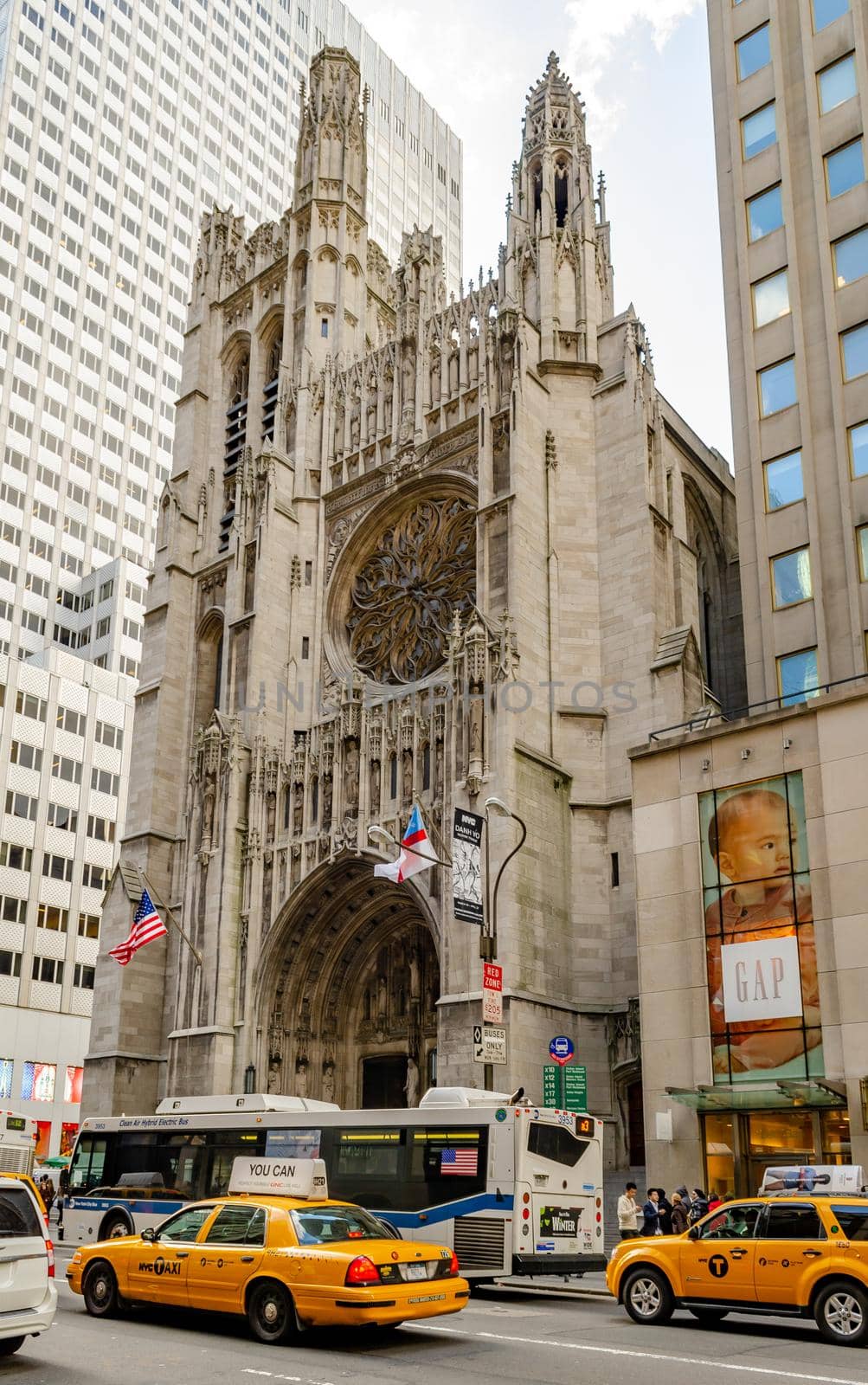 Saint Thomas Church with Bus and yellow taxis in front, GAP Store, Manhattan, New York City during winter day, vertical