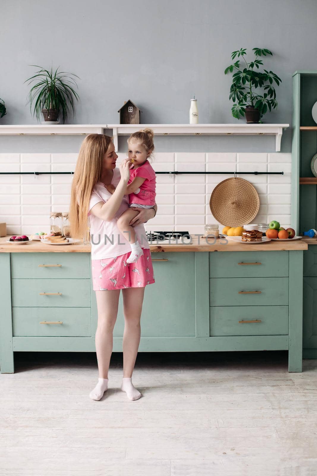 Mother having breakfast with her lovely daughter in the kitchen. by StudioLucky