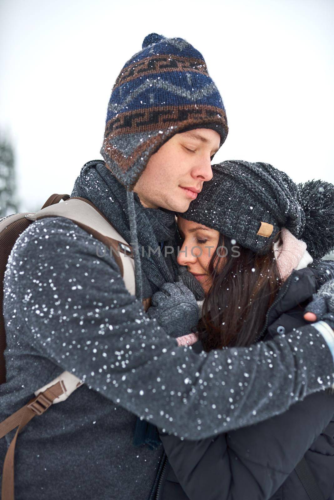 Ill keep you warm. Shot of a happy young couple enjoying themselves while being out in the snow. by YuriArcurs