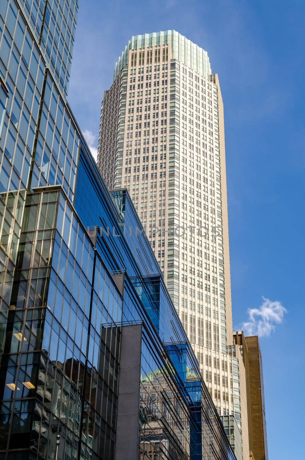 Office Building Skyscraper at Fifth Avenue view from low angle with blue glass Building facade in front, New York City during sunny winter day with clear sky, vertical