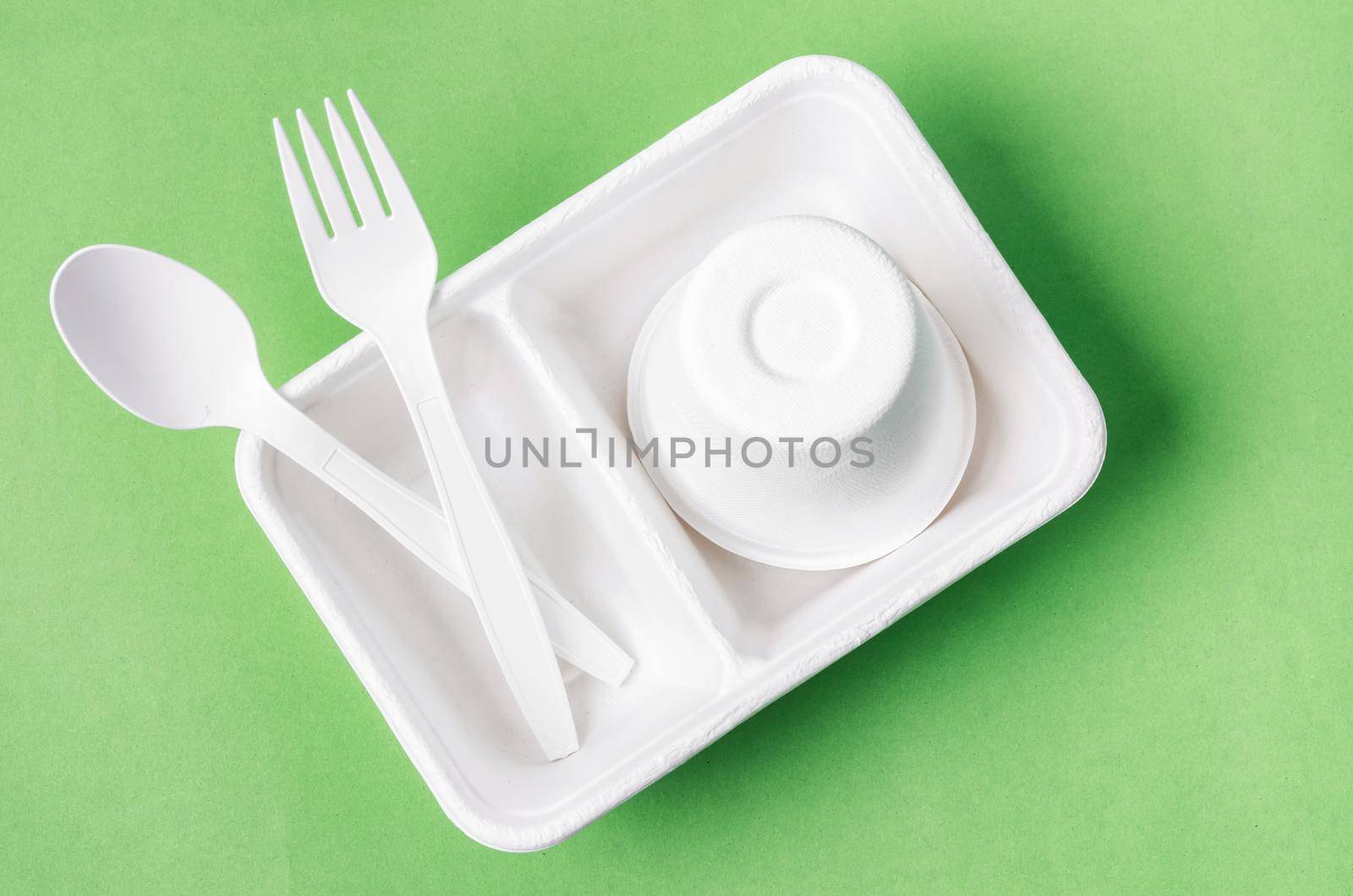 Eco friendly biodegradable paper disposable for packaging food on green background.