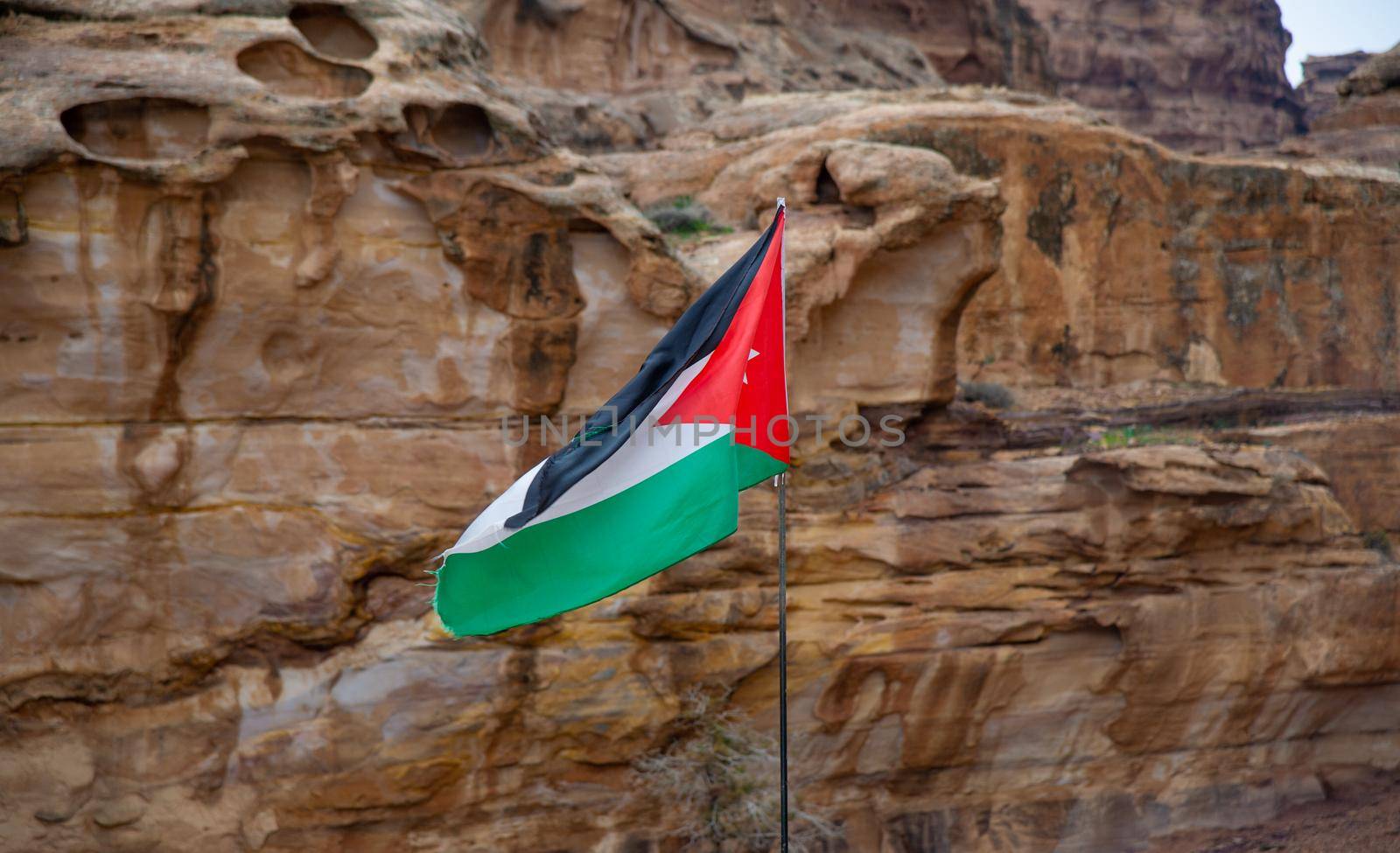 The flag of Jordan flies in Petra and beautiful red mountains can be seen in the background 20 February 2020