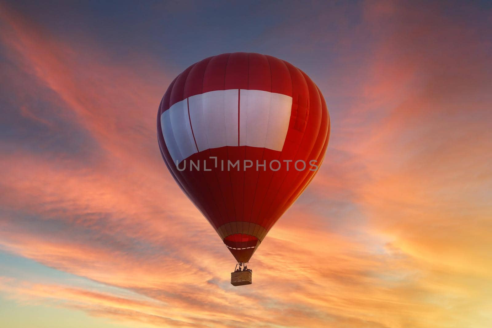 Red hot air balloon flying in the sky at sunset or sunrise. High quality photo
