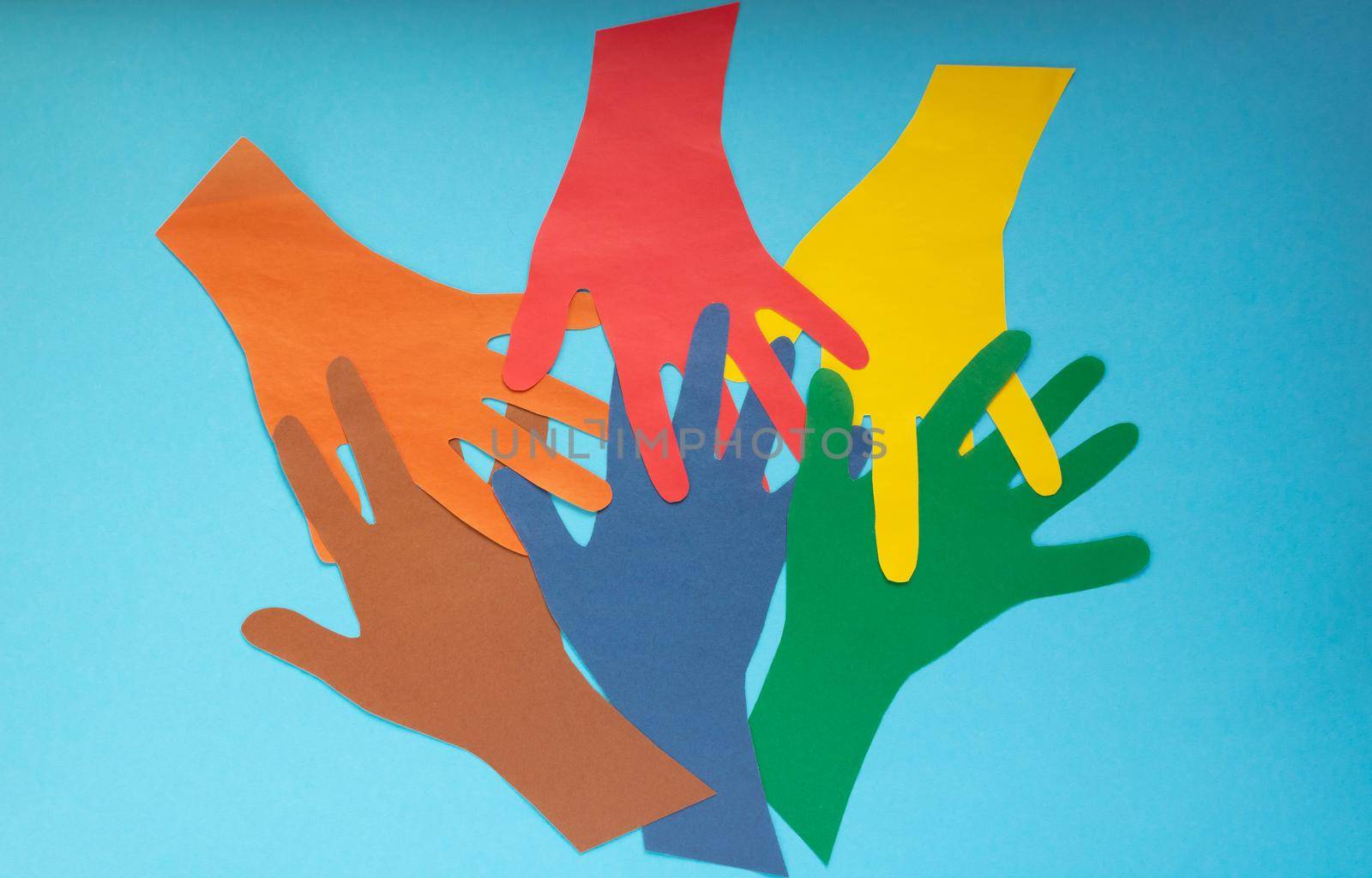 Abstract background open multicolored paper palms on a blue background.The concept of Autism Day and Youth Solidarity Day by lapushka62