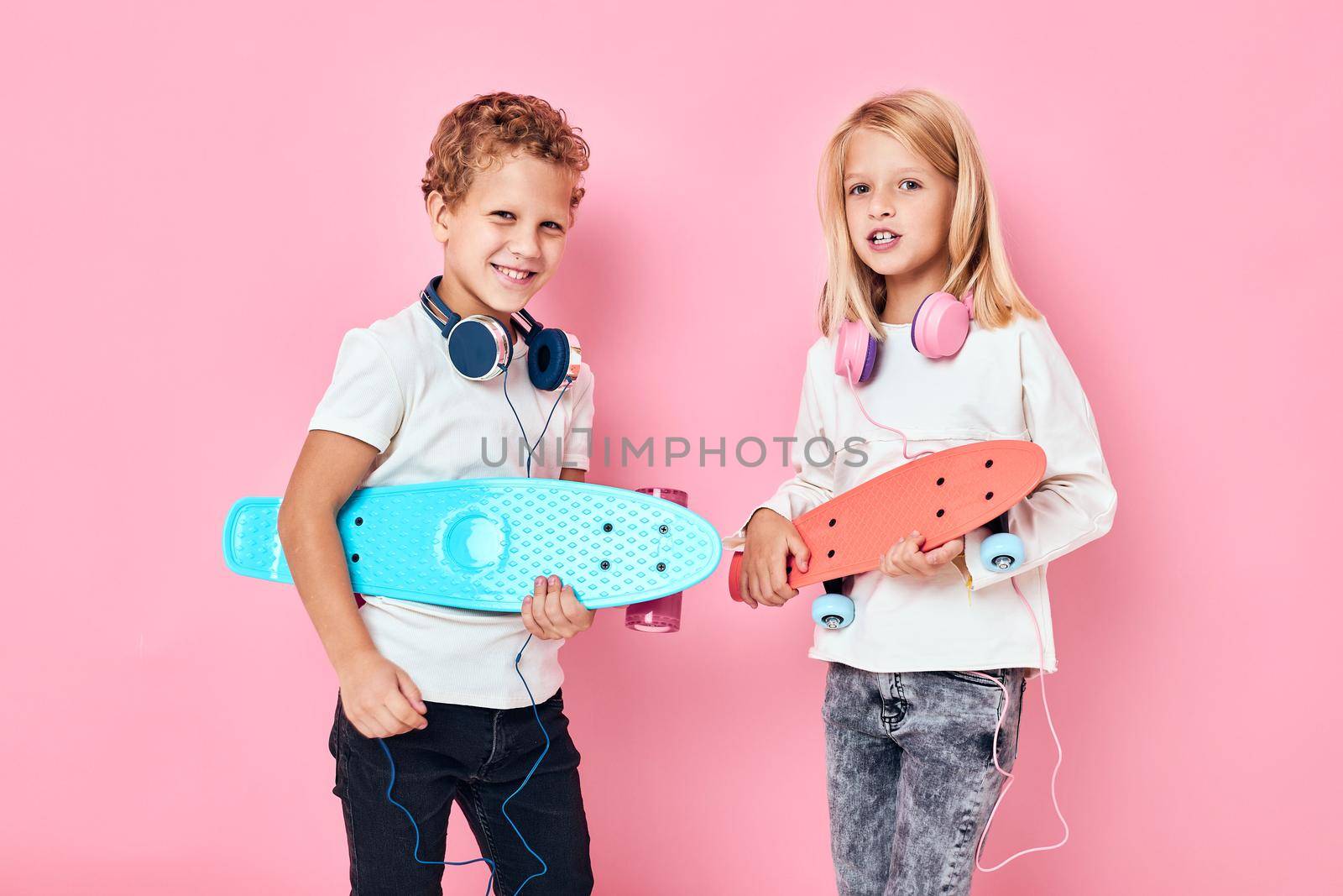 Funny children in headphones skateboards in hands isolated background. High quality photo