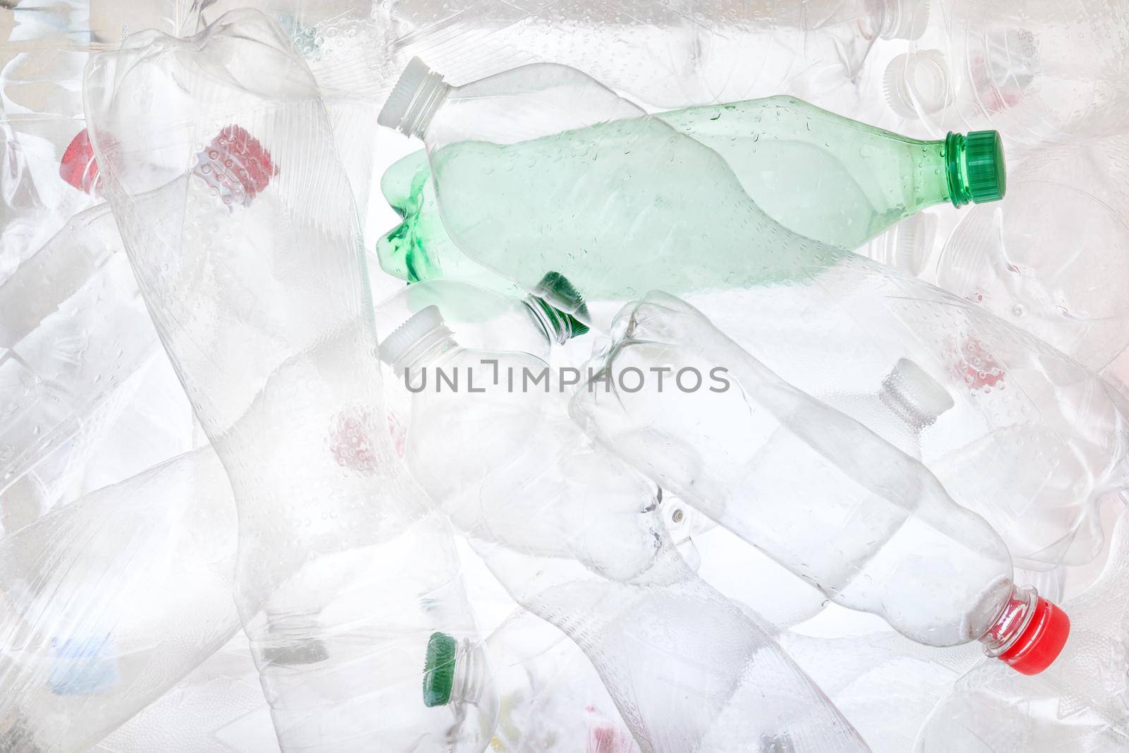 Empty plastic bottles background. Water PET bottle recycling plastic material recyclable waste sorting. Recyclable trash recycle garbage concept. Many bottles transparent plastic PET recycling waste by synel