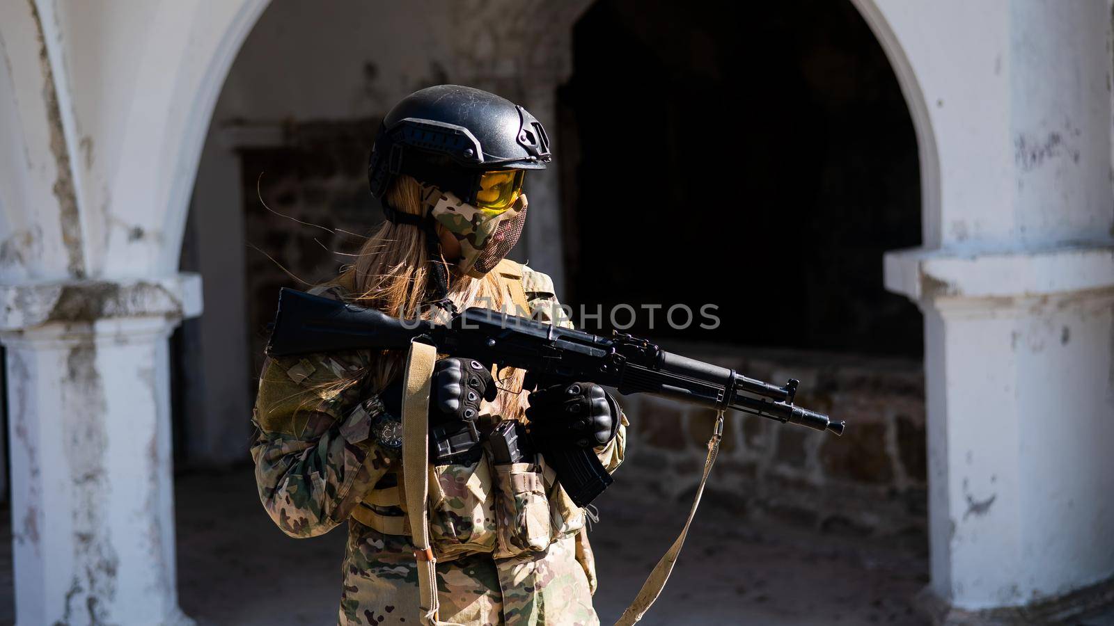 Caucasian woman in a protective suit with a machine gun. A female soldier in a camouflage uniform holds a weapon. by mrwed54